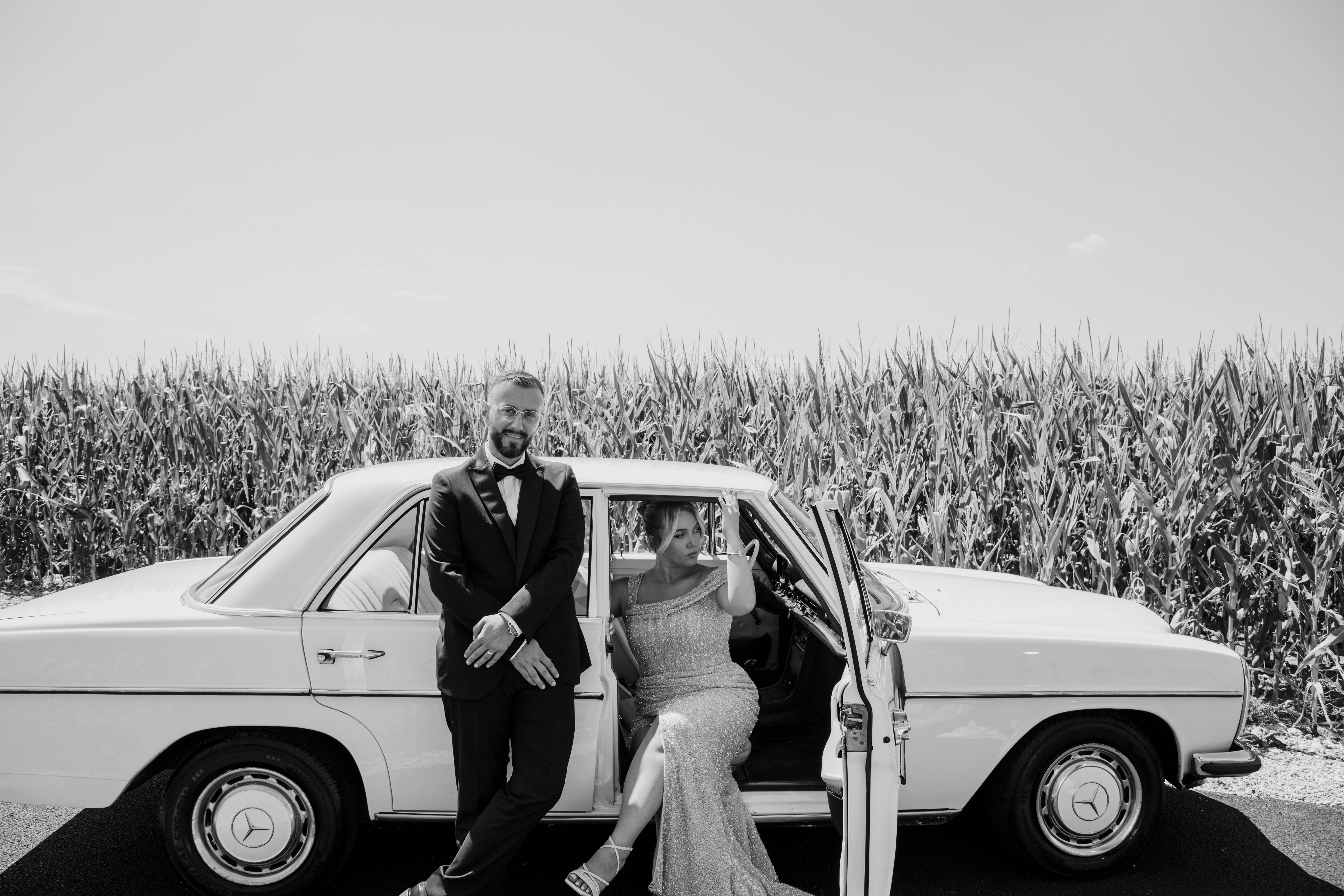 Couple posing with a vintage car near a cornfield