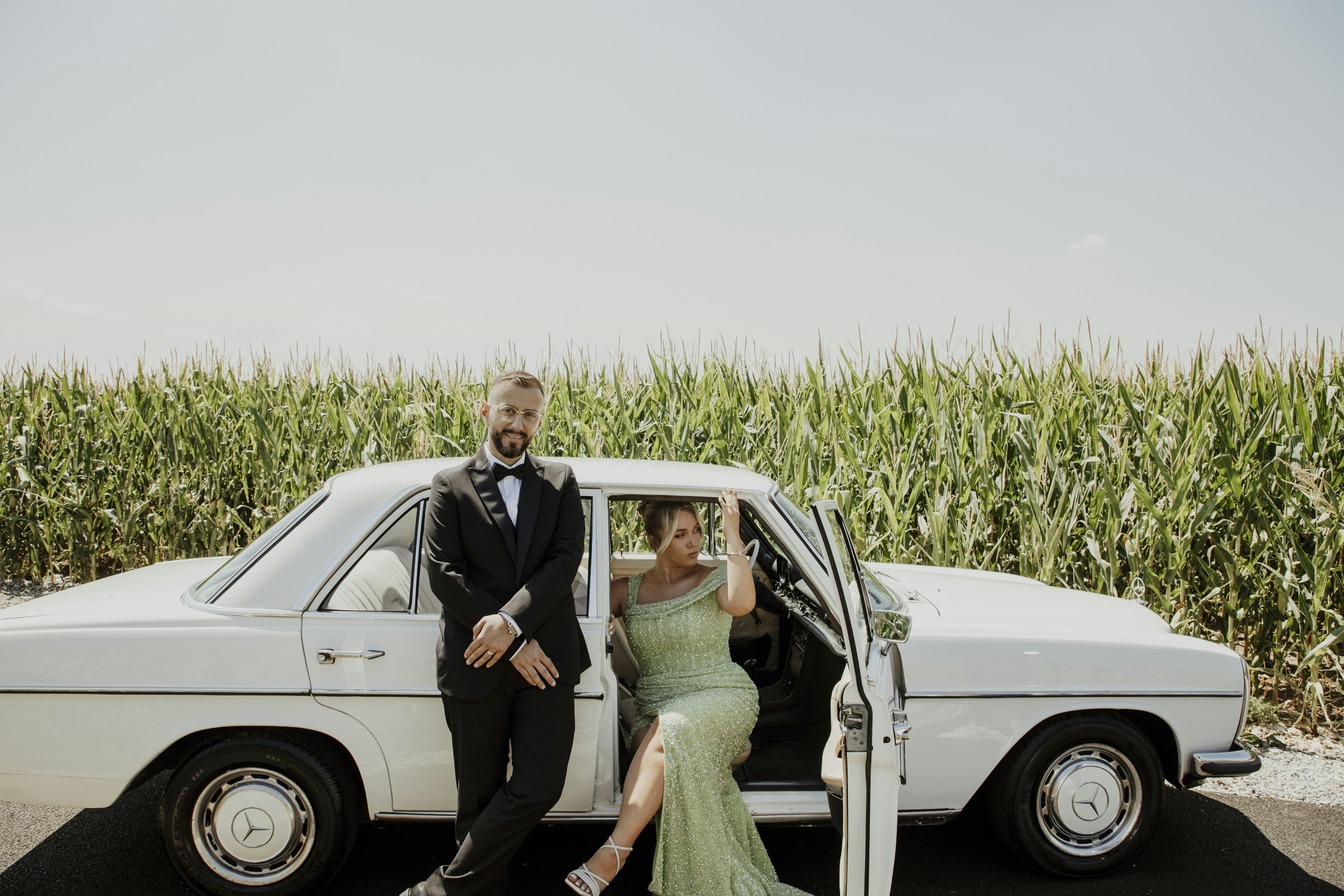 Couple in formal attire with vintage car in field
