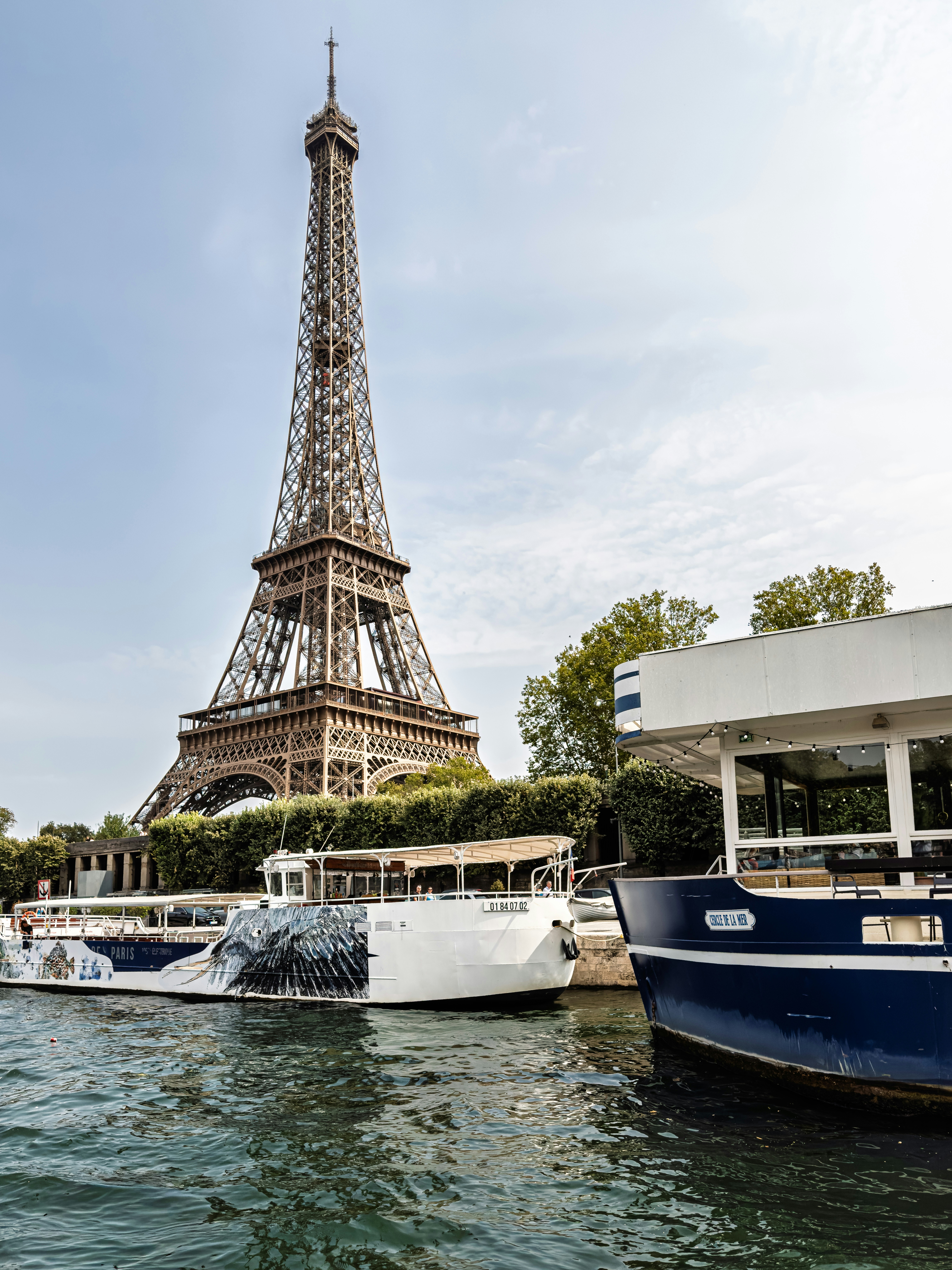 Eiffel tower with boats on the seine river.