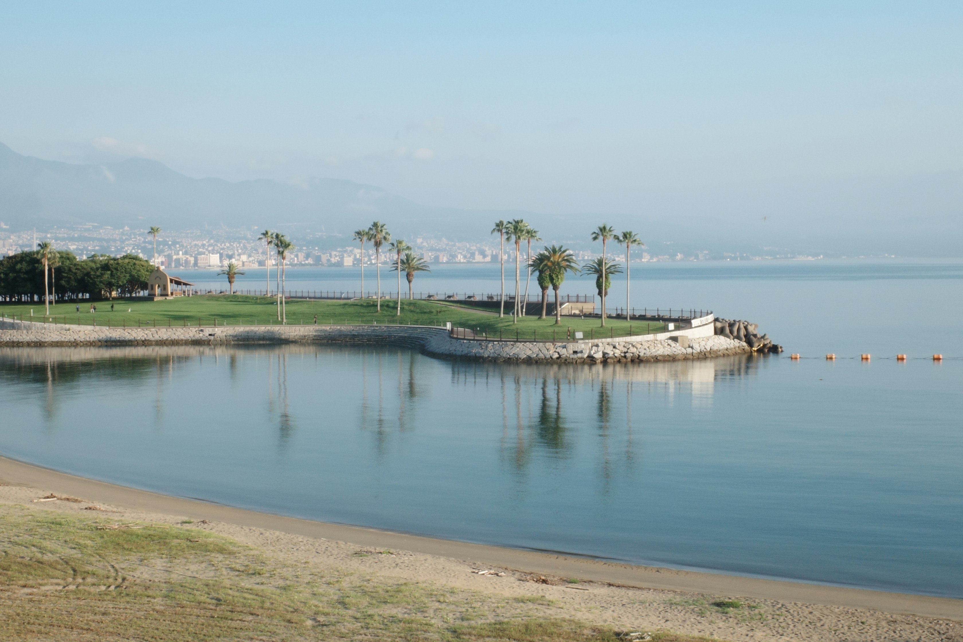 Calm water reflects palm trees on a small island