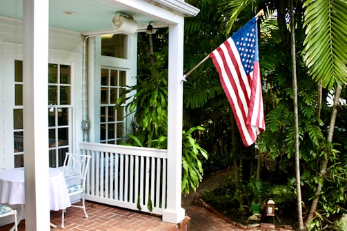 American flag on a porch with lush greenery