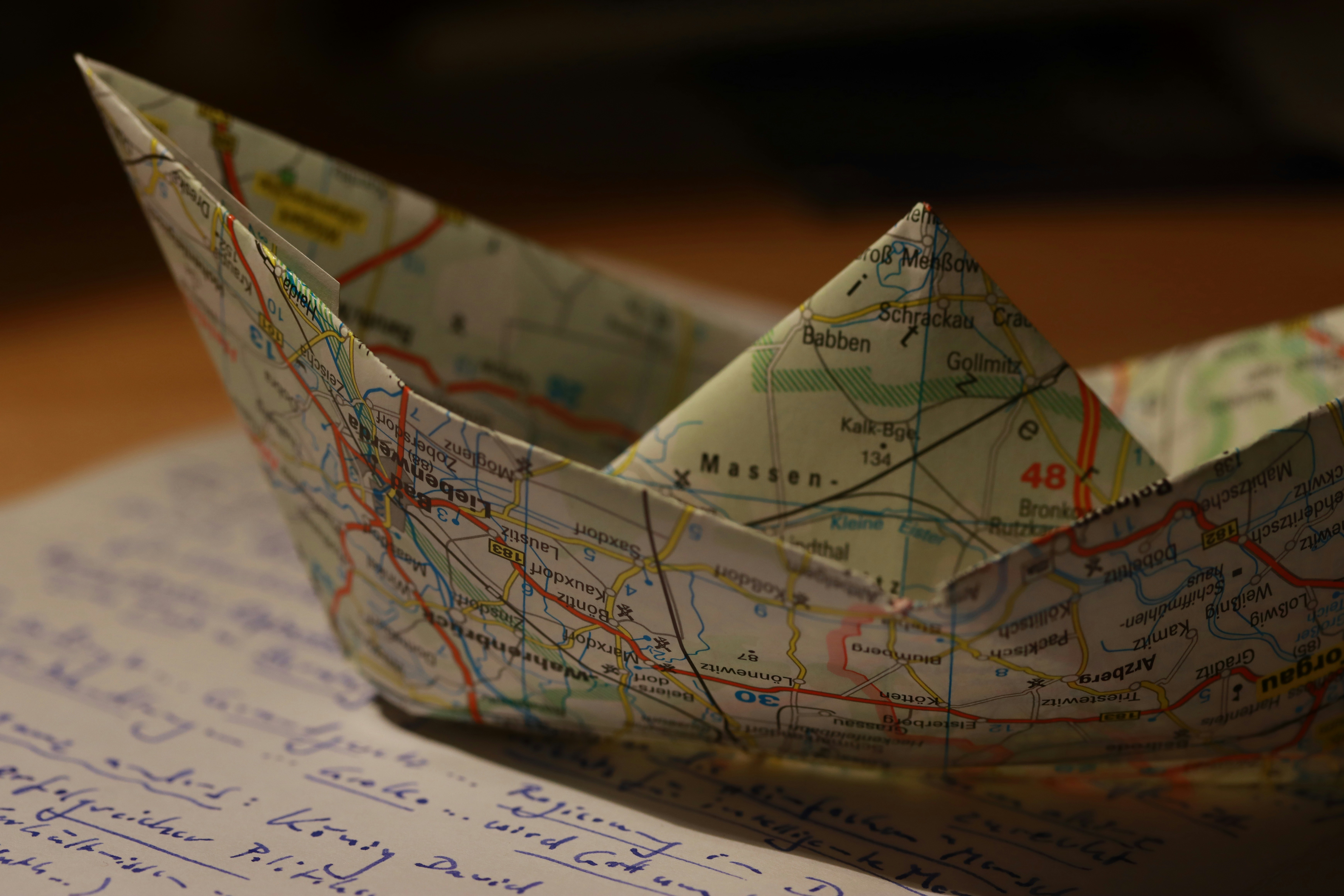 Perahu kertas yang terbuat dari peta bertumpu pada tulisan.