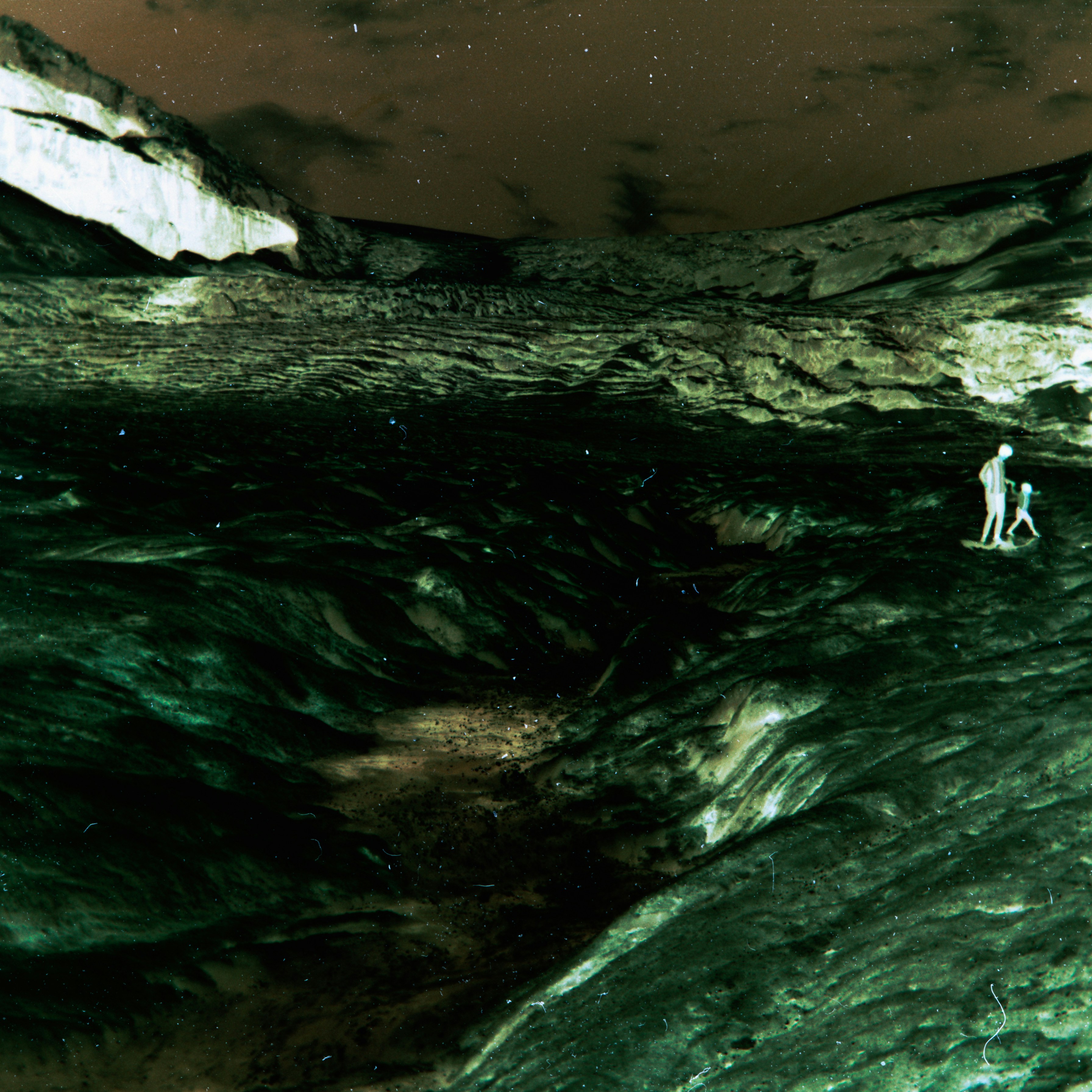 Two figures walk across a rocky, alien landscape at night.