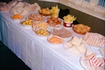 A table laden with various party snacks and sandwiches.