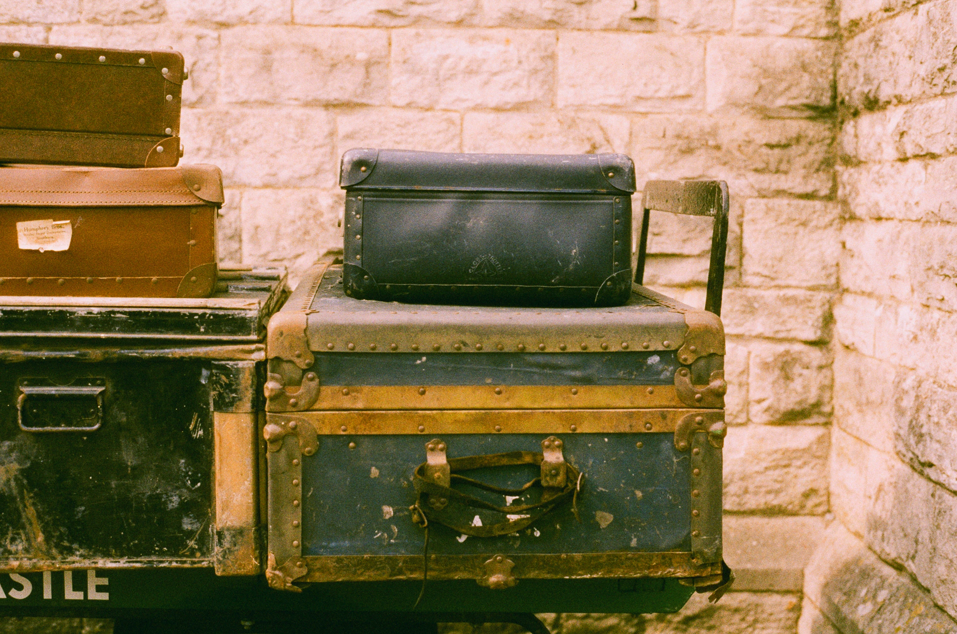 Vintage luggage stacked against a stone wall