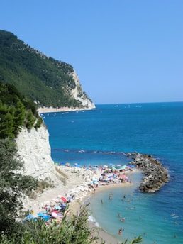 Crowded beach with umbrellas and people enjoying the ocean.