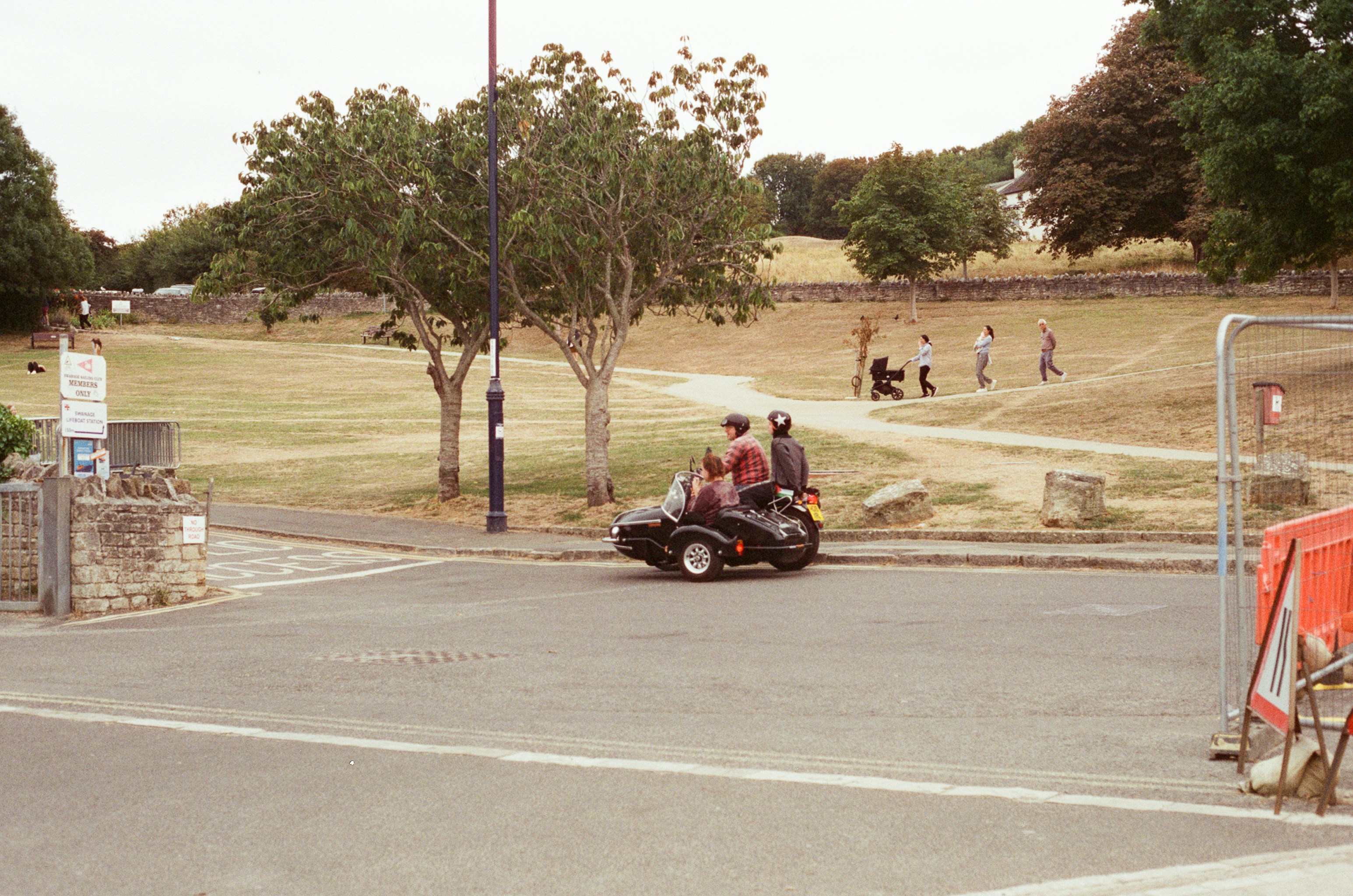 Two people ride a three-wheeled vehicle on a street.