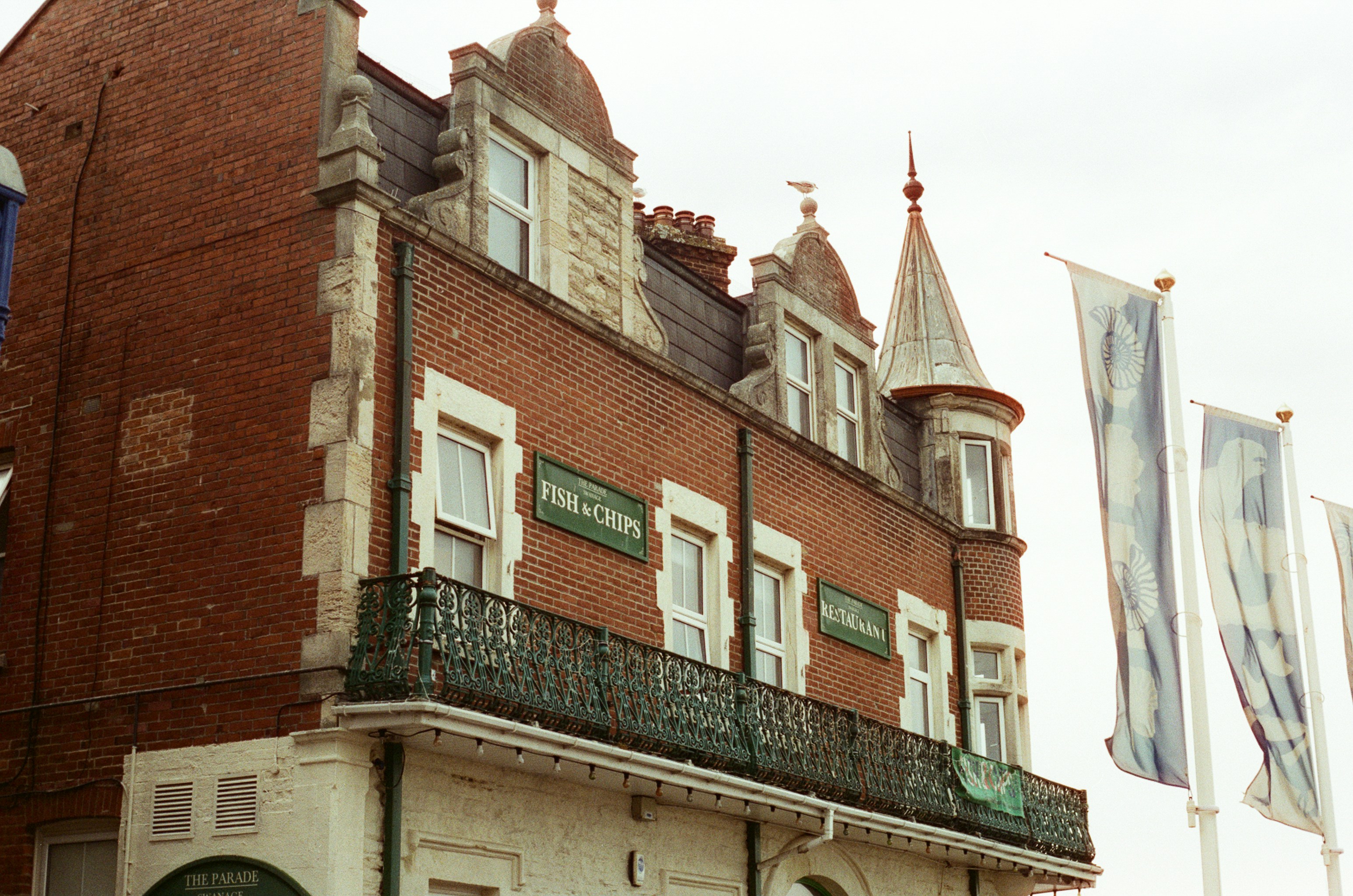 Red brick building with ornate balcony and flags