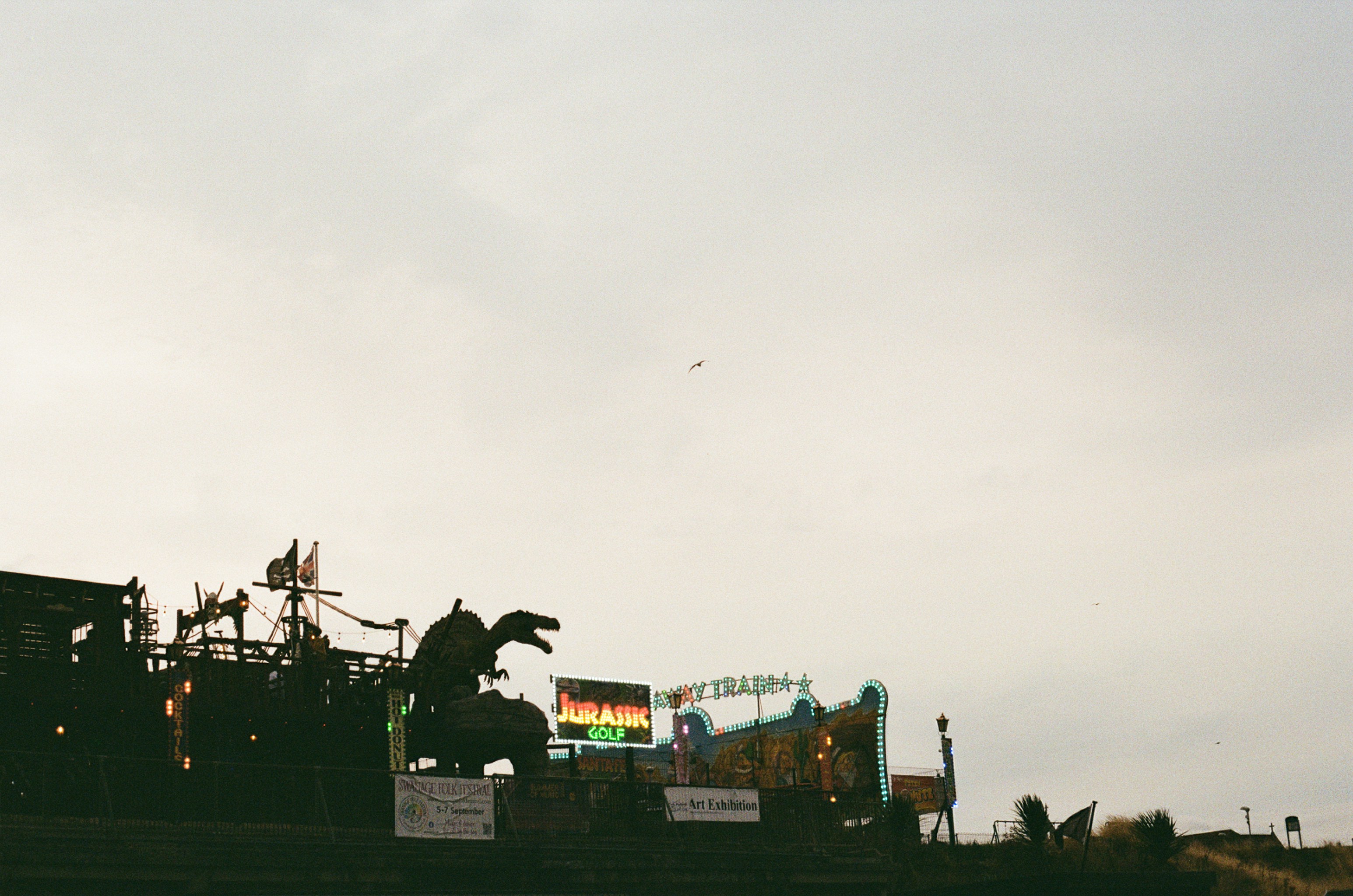 Dinosaur statue and Jurassic Golf signage at a festival.