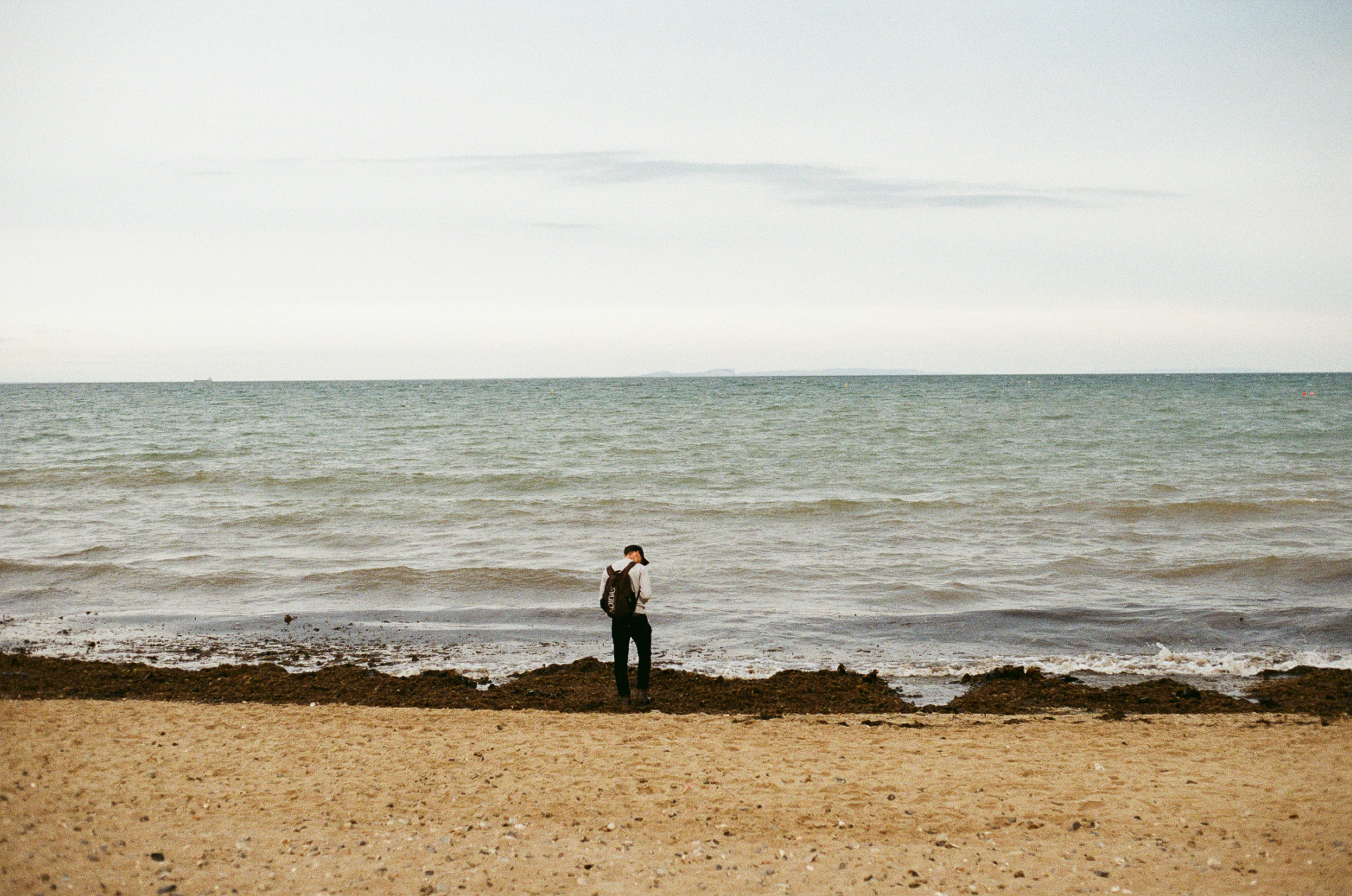 Person standing on a sandy beach by the ocean.