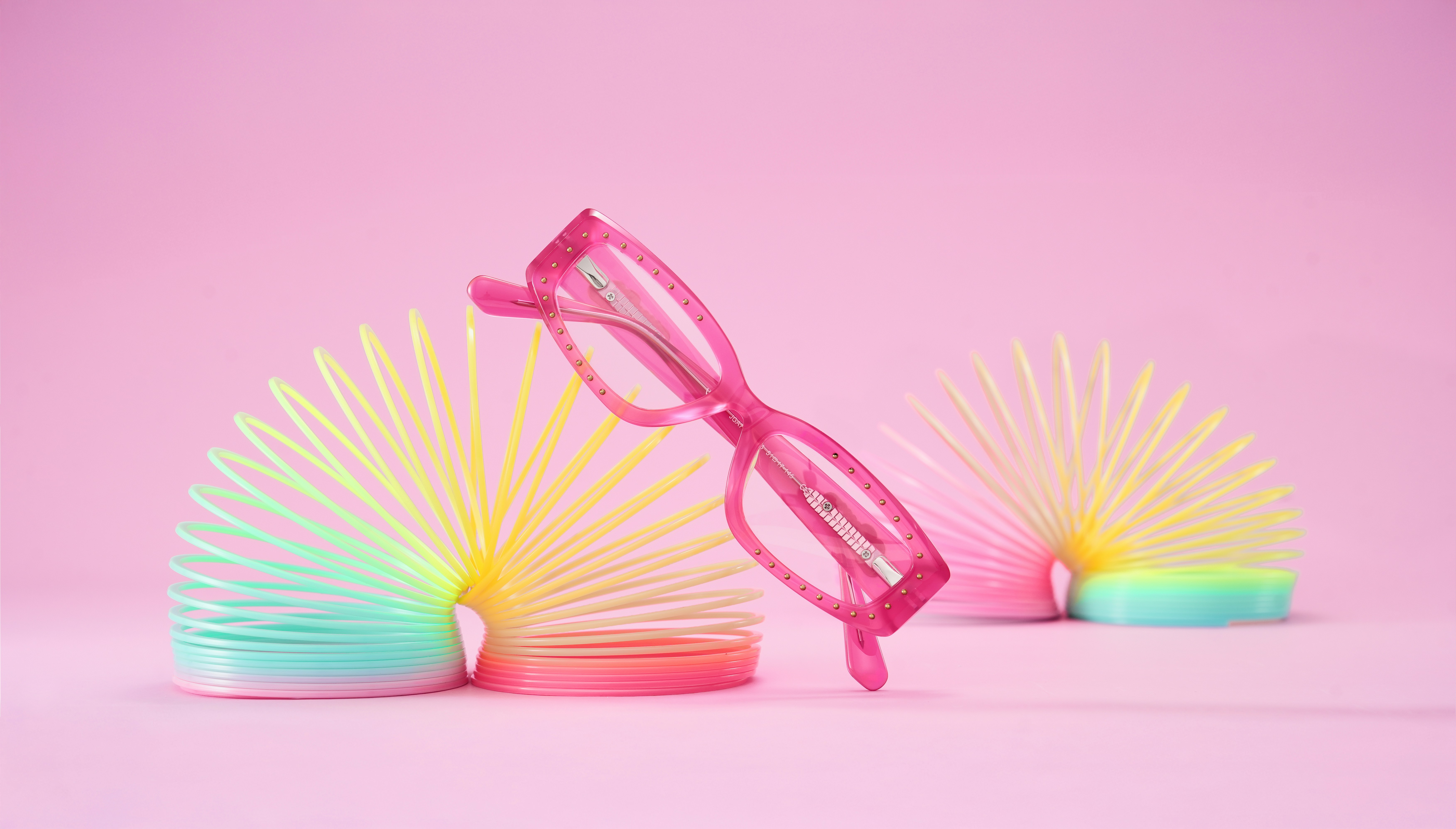 Pink glasses resting on colorful slinky toys