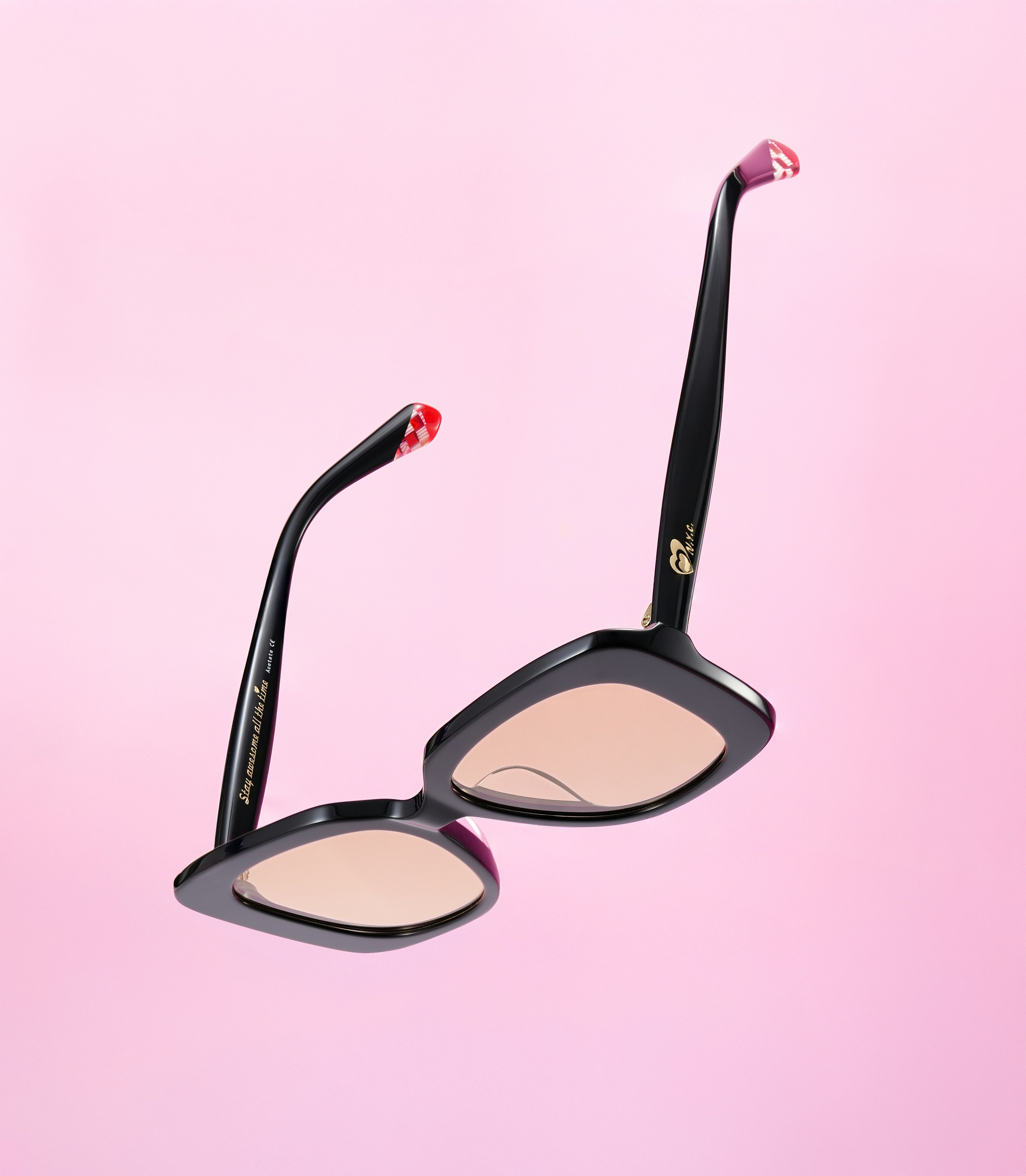 Óculos de sol pretos com detalhes em rosa no fundo rosa