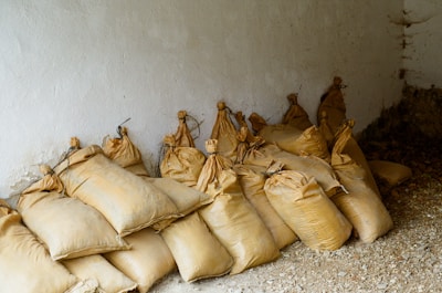 Many burlap sacks piled against a white wall.