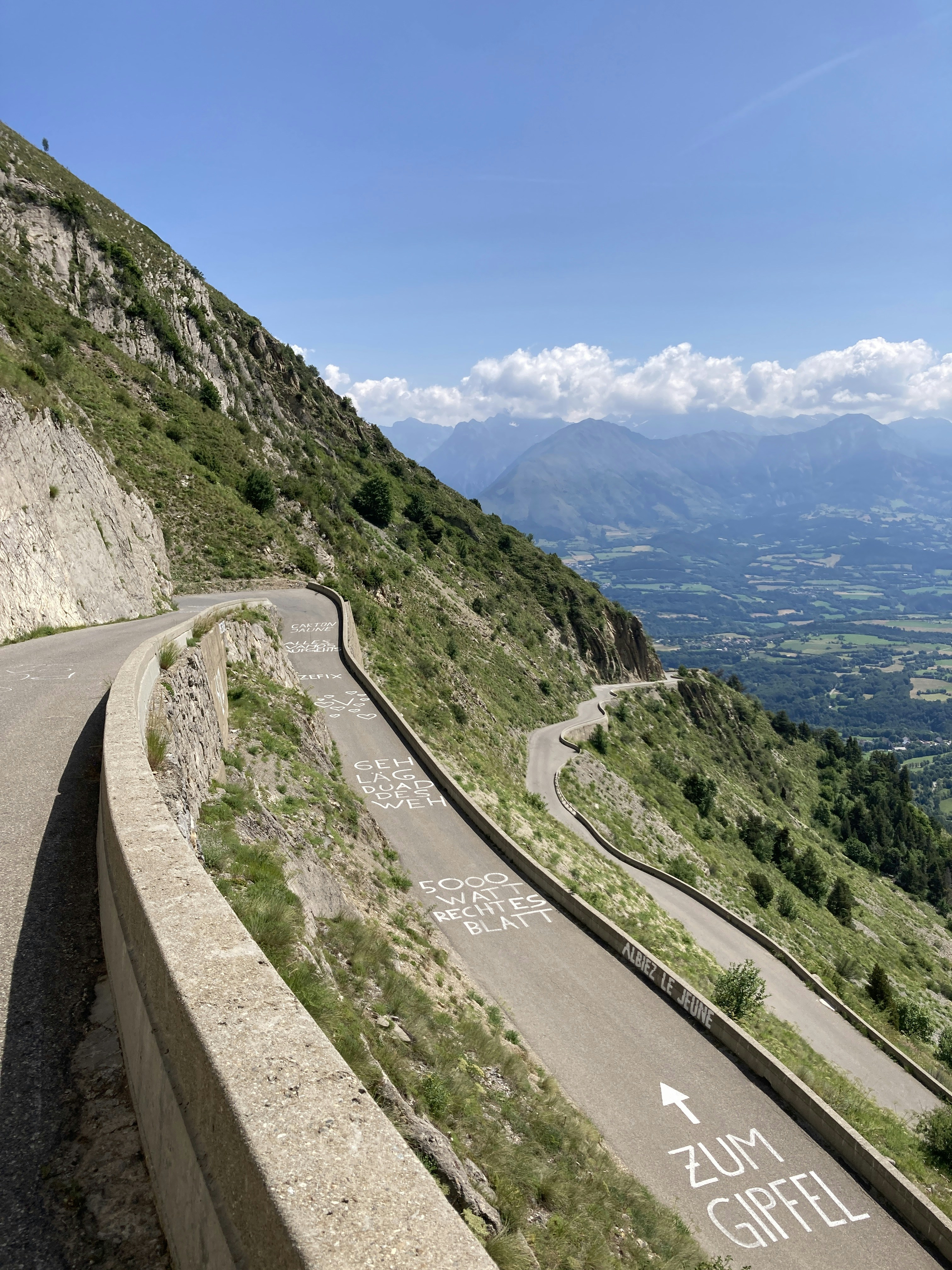 Route de montagne sinueuse avec des panneaux indiquant le sommet