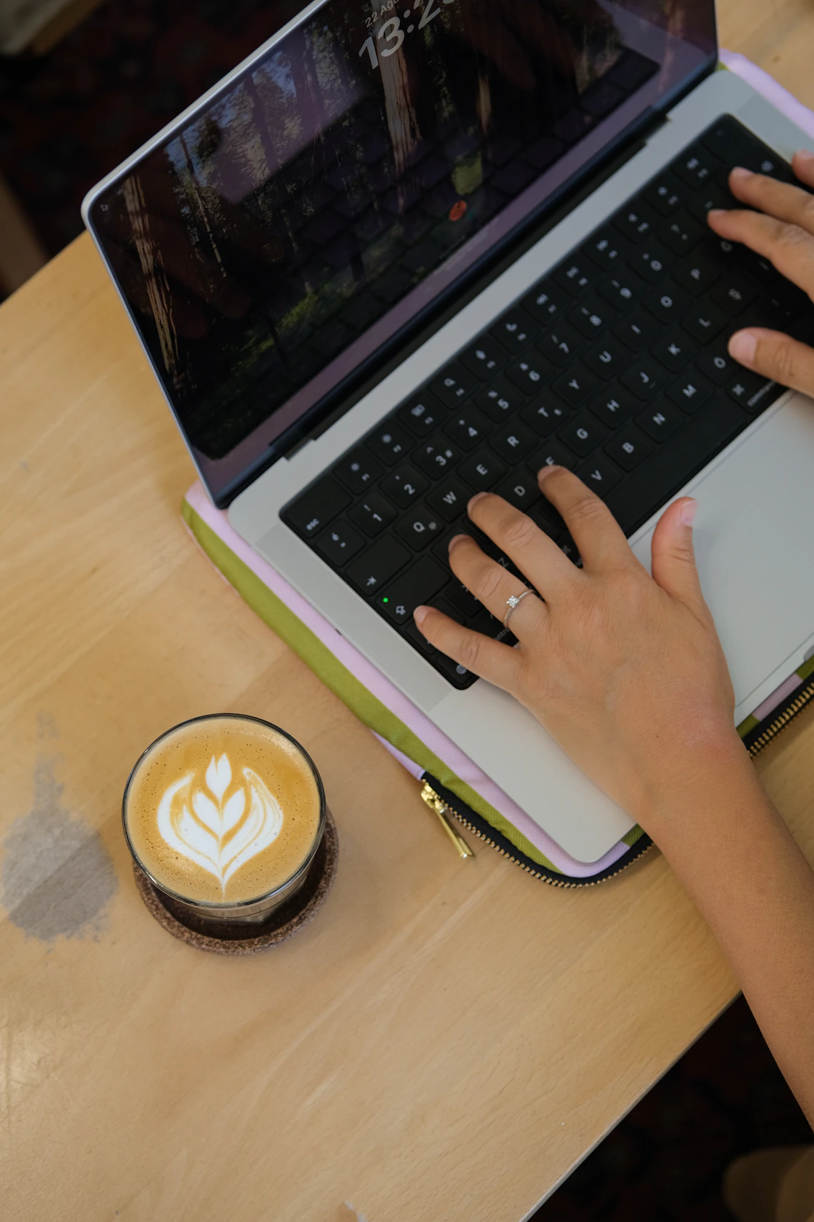 Hands typing beside a cup of coffee