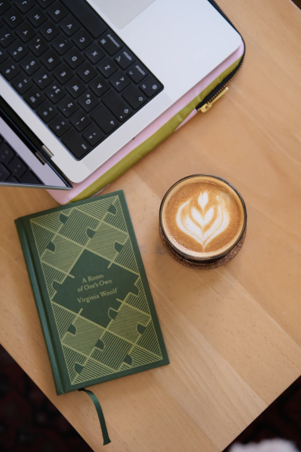 Laptop, book, and latte on a wooden table in a calm workspace