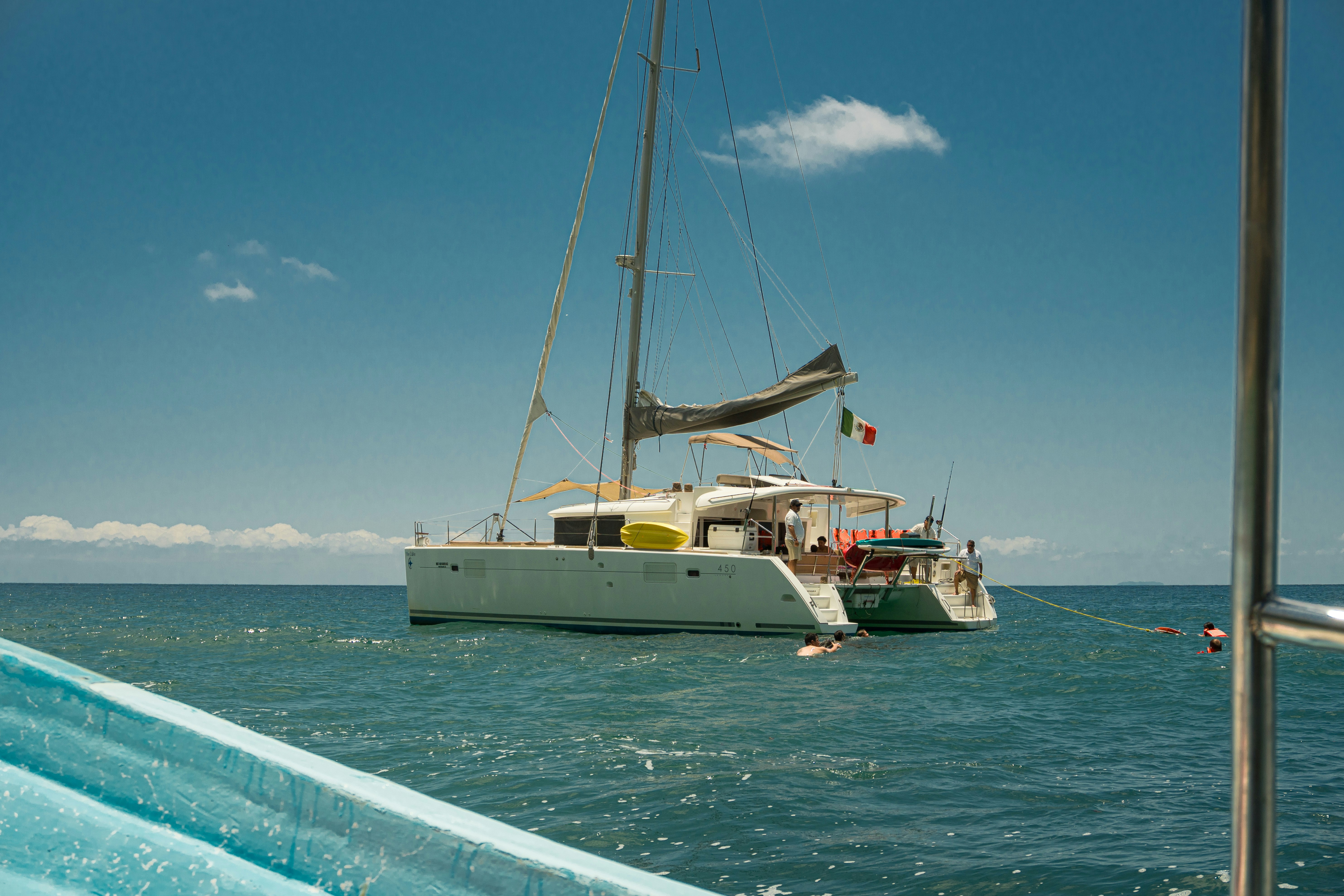 A white catamaran anchored in the ocean under a blue sky.