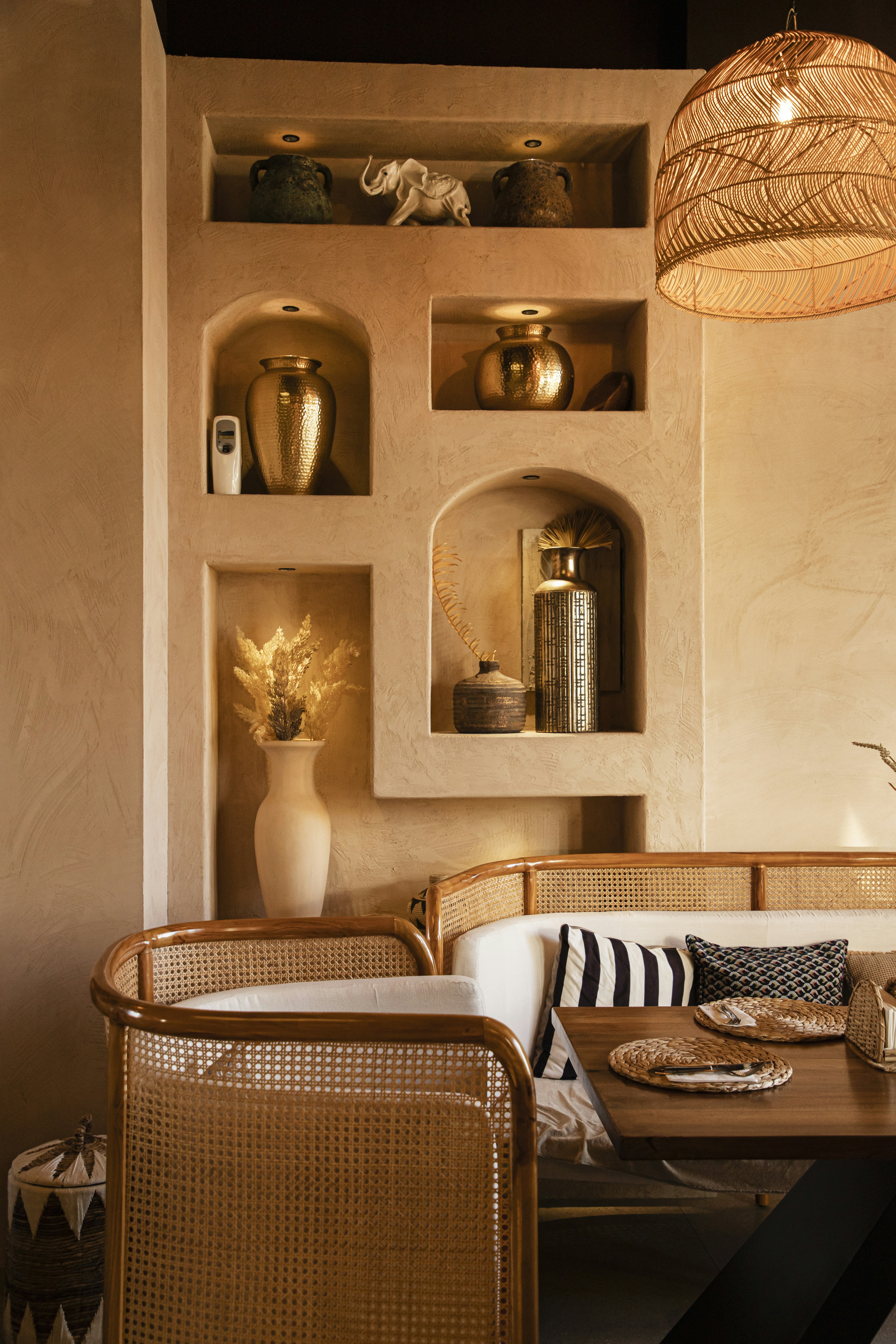 Cozy dining nook with woven chairs and decorative shelves.