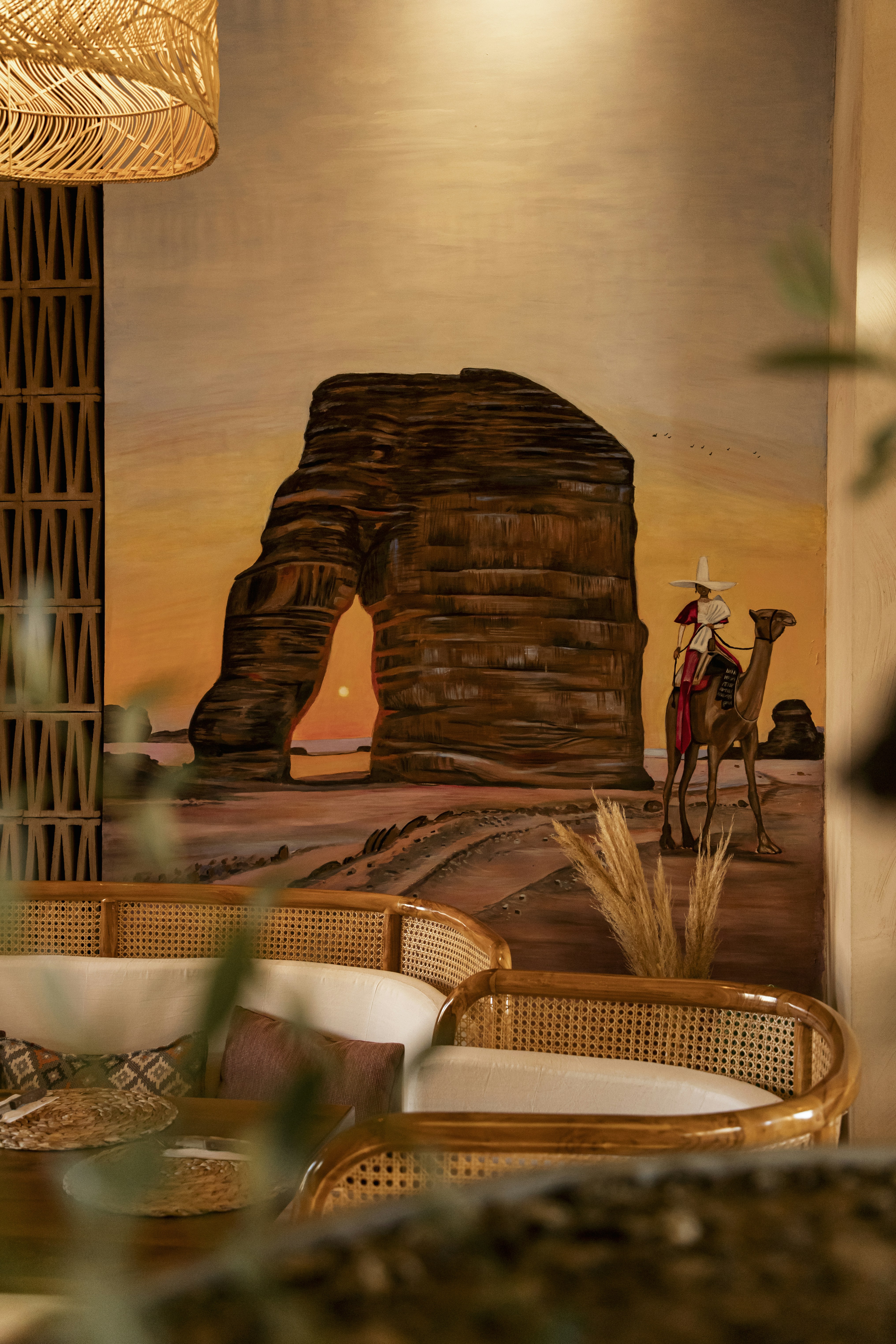 Mural of desert landscape with camel rider and arch.