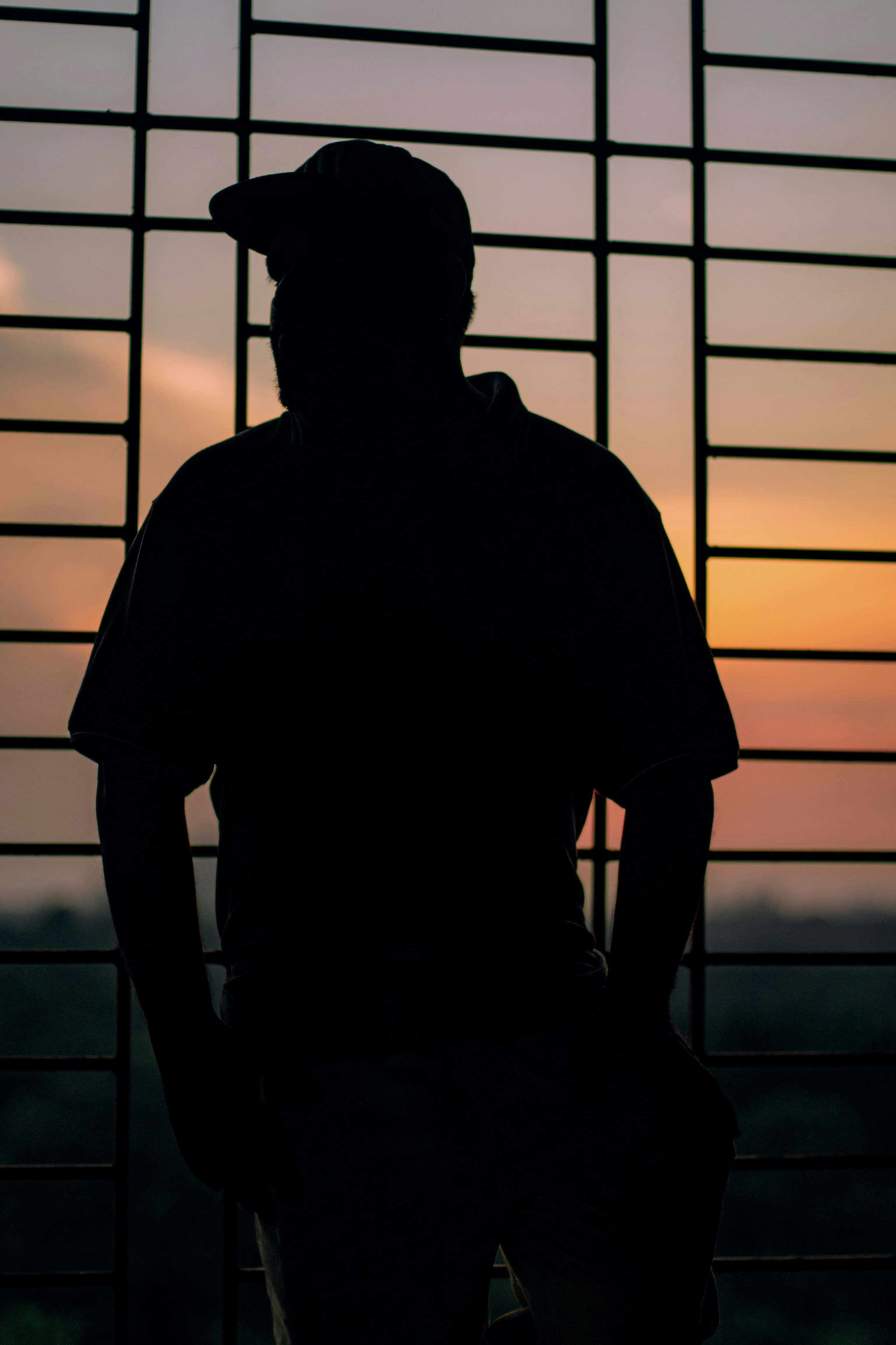 Silhouette of a man wearing a baseball cap at sunset.