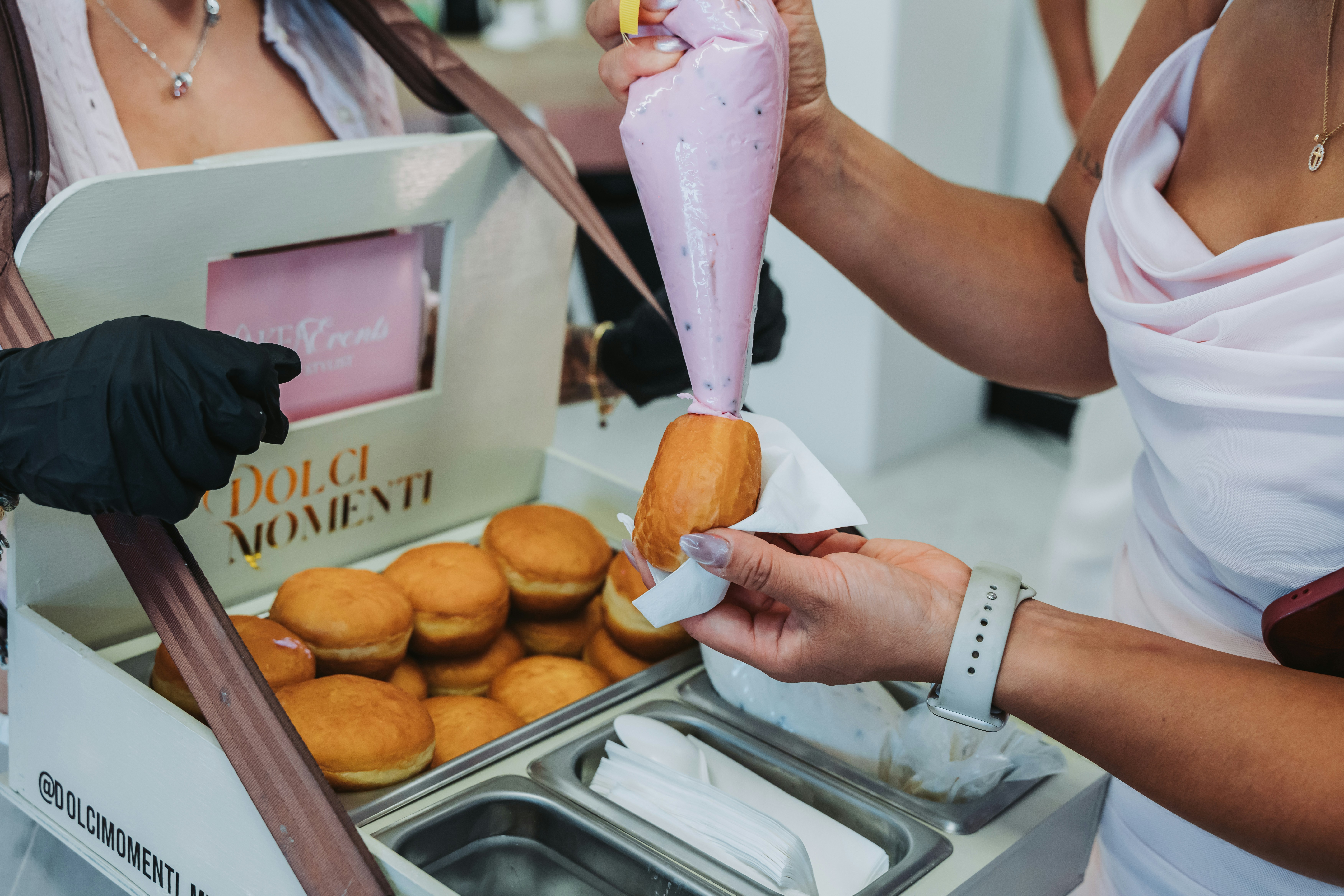 Quelqu’un remplit des beignets de crème à l’aide d’une poche à douille.