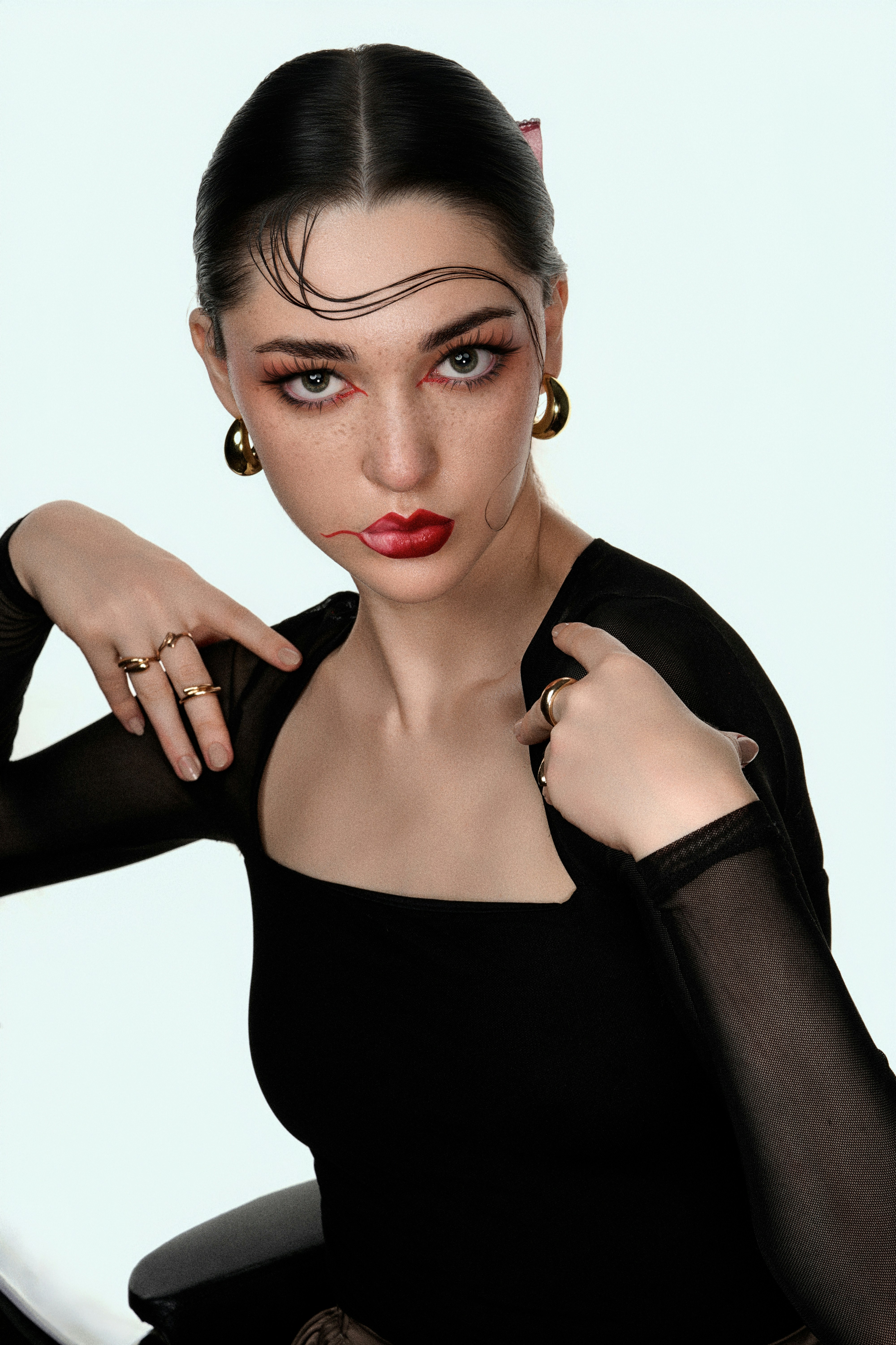 Woman with striking makeup and jewelry poses confidently poses