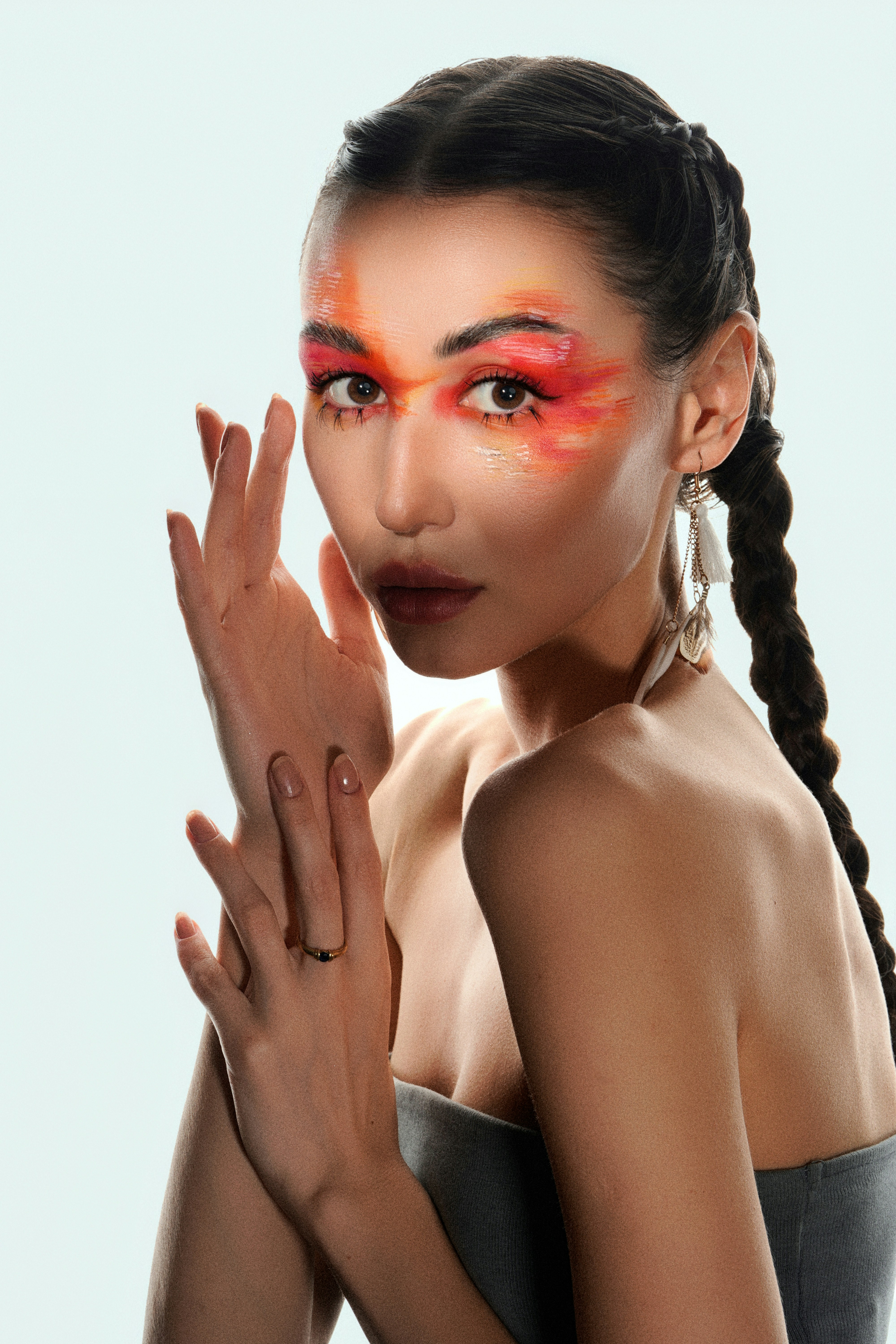 Woman with striking red and orange face paint and braid.