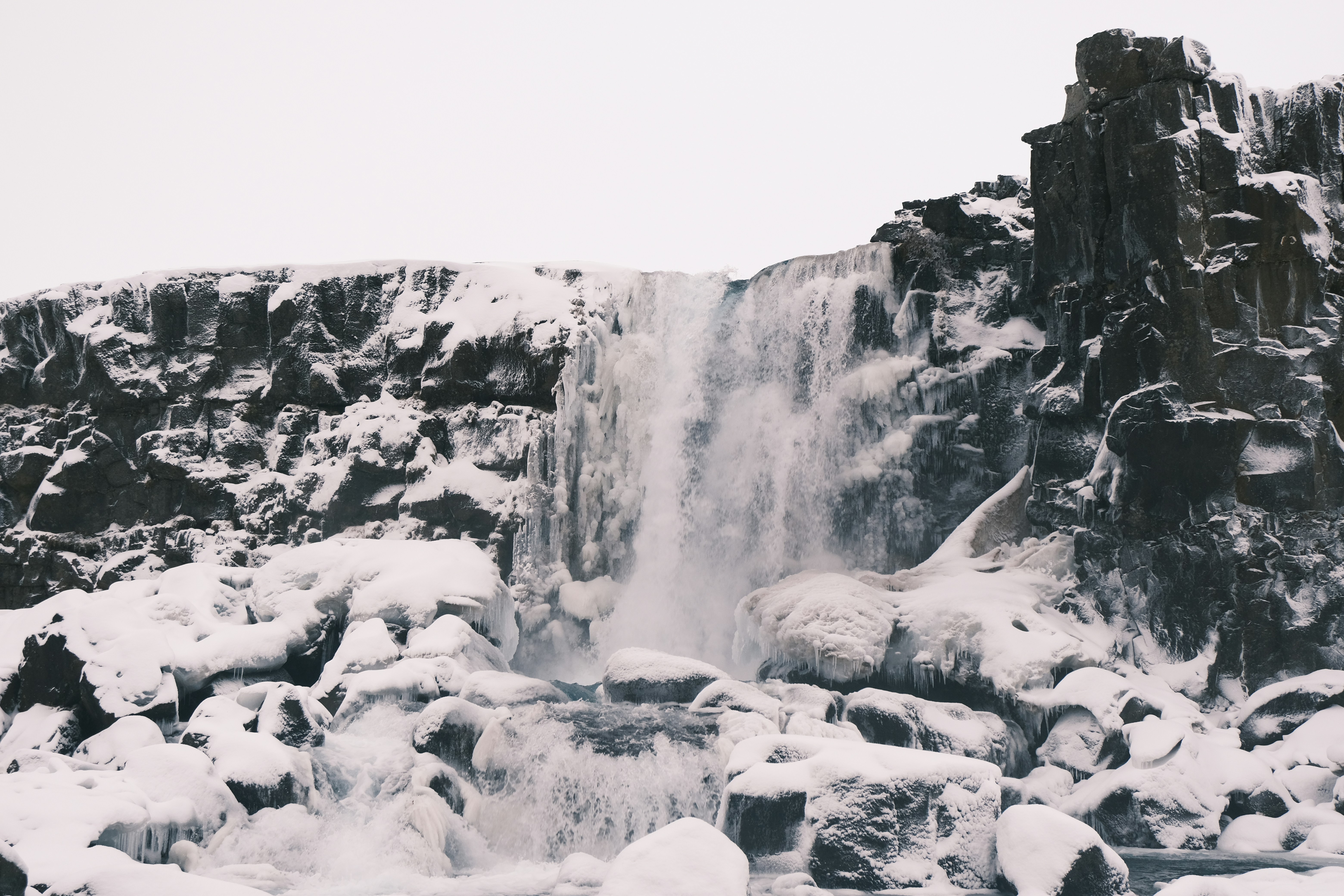 Cascata ghiacciata che cade su rocce innevate
