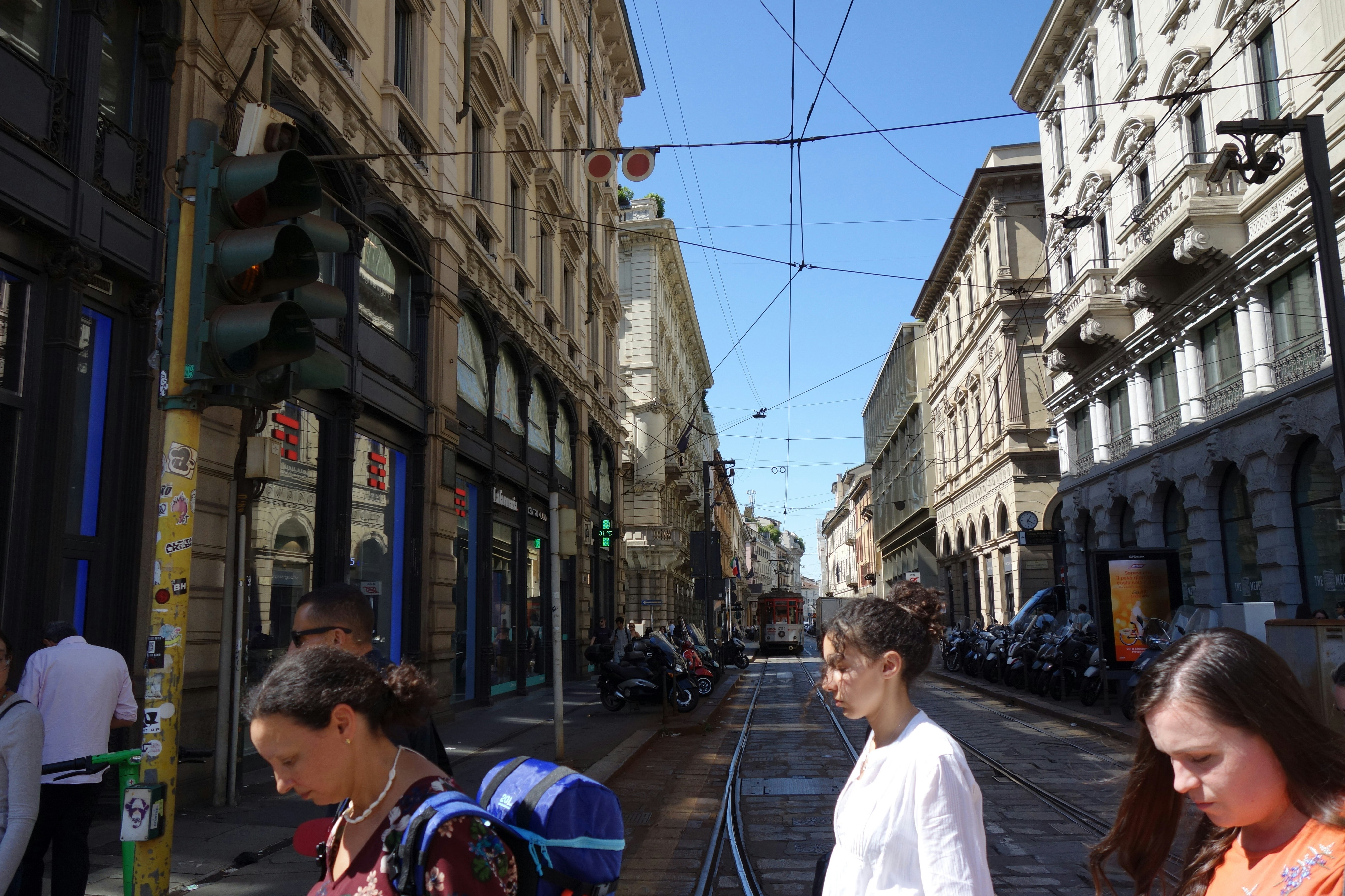 People walk down a city street with buildings.