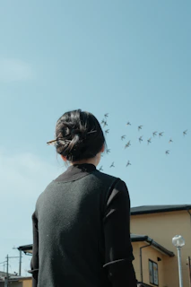 Woman watches birds fly in a clear blue sky