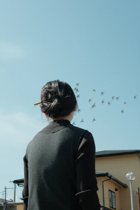 Woman watches birds fly in a clear blue sky