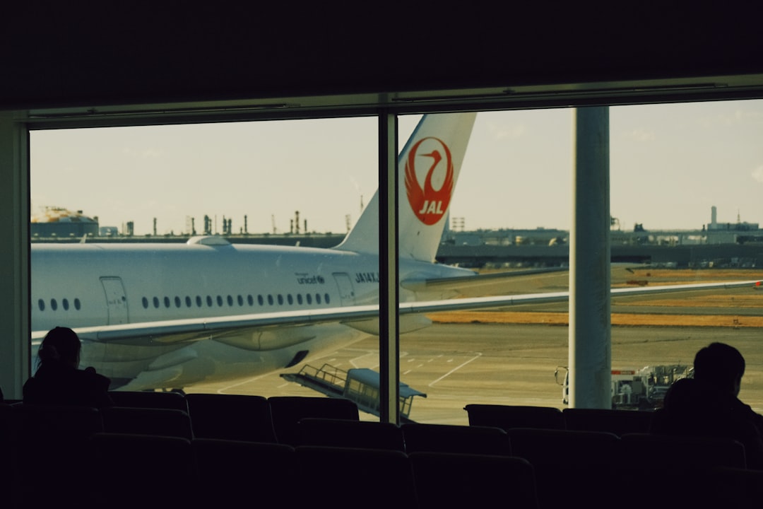 Airplane at airport gate seen through window Via Unsplash (by Will Xiang)