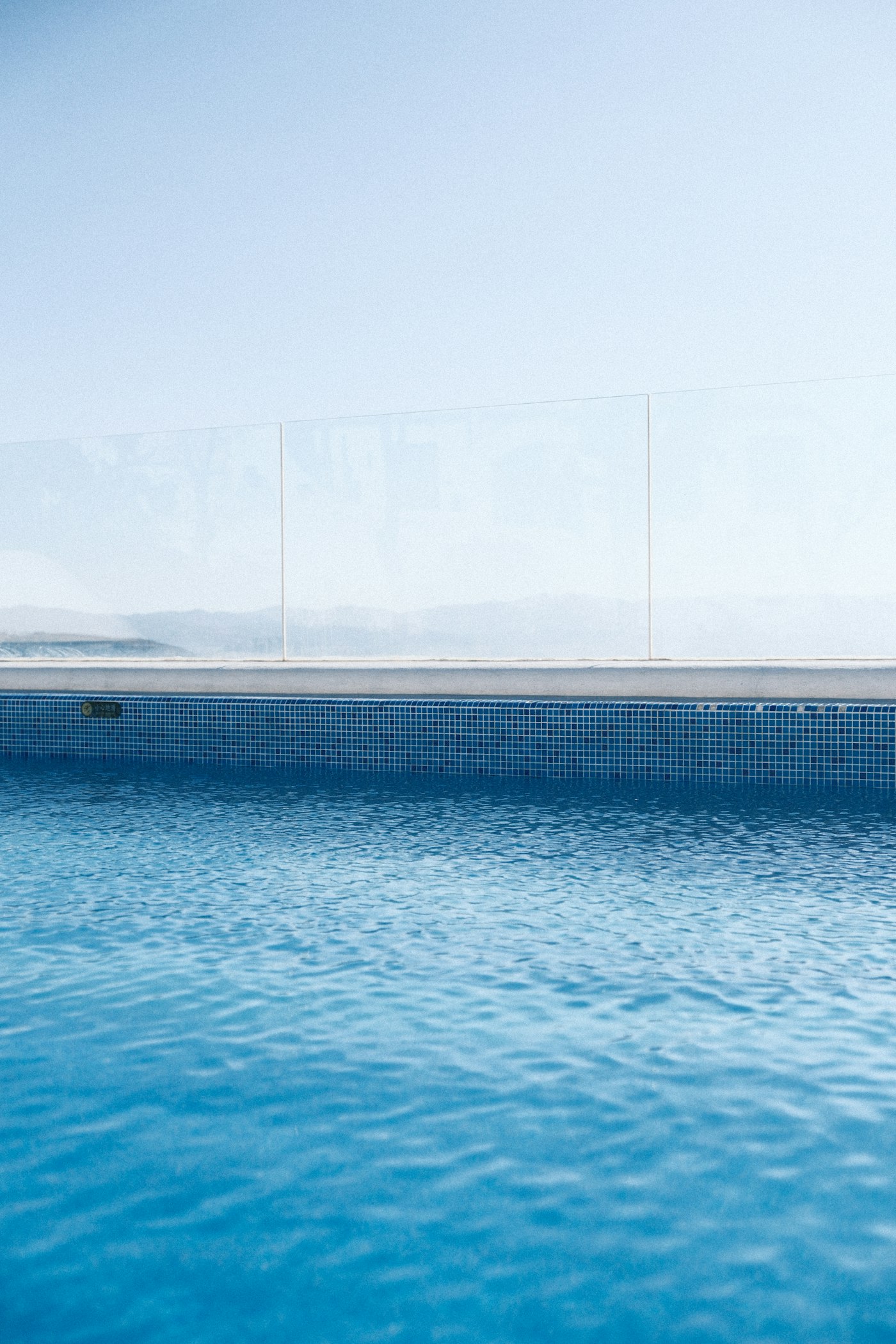 Frameless glass pool fence above clear blue swimming pool water
