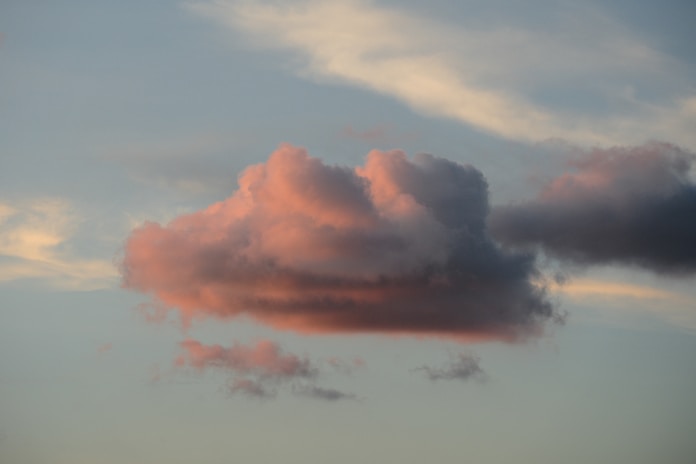 Pink and gray clouds in a pale blue sky