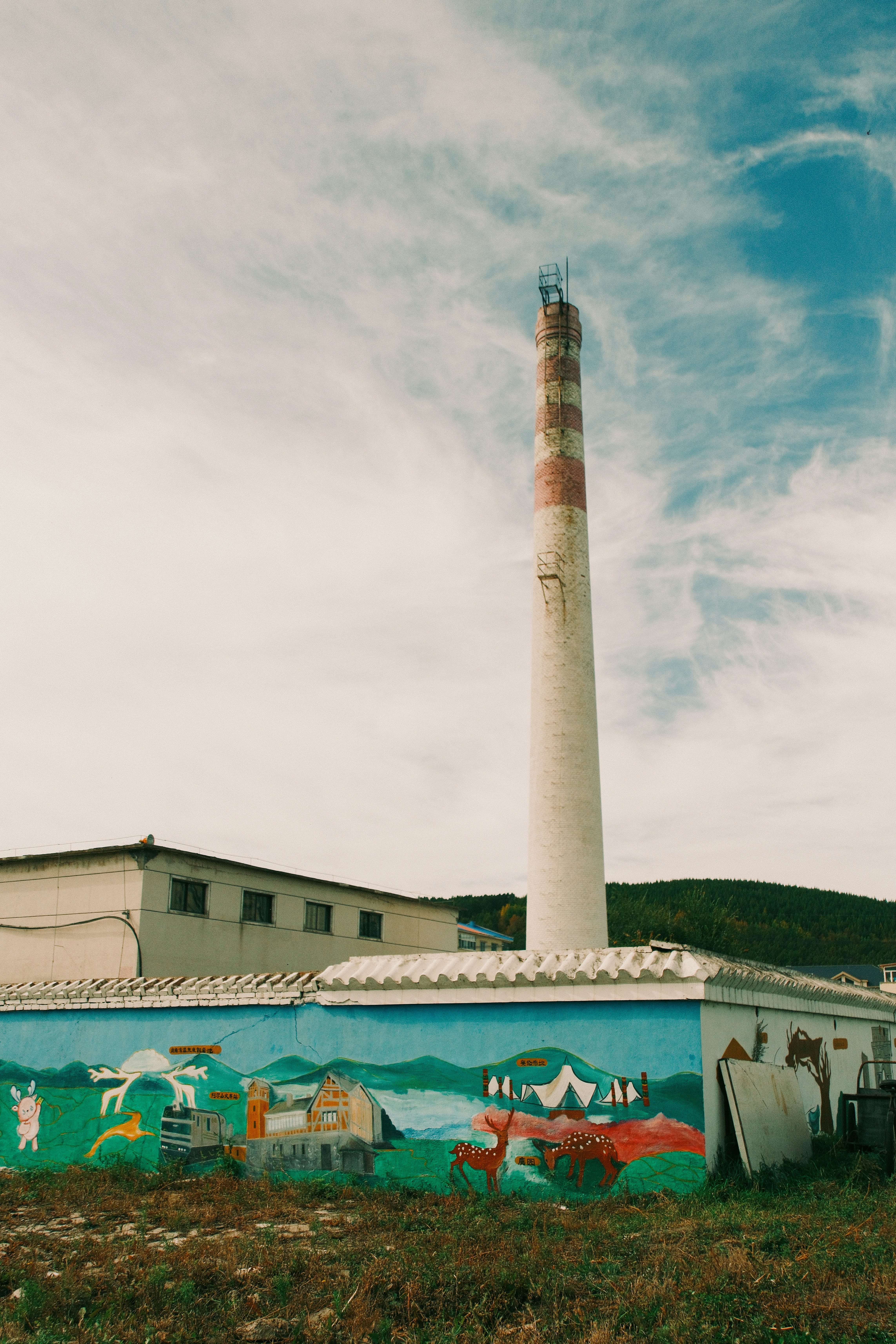 Chimenea industrial alta con pared mural de colores.