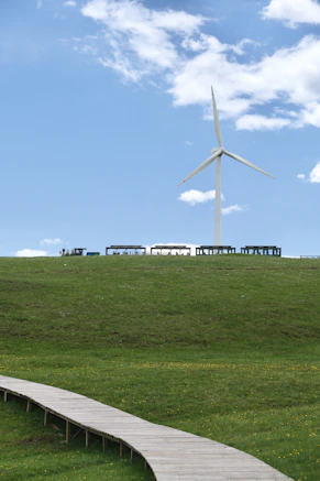 Wind turbine on a grassy hill under blue sky