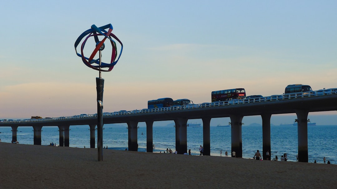 Pier with traffic and a wind sculpture at sunset,