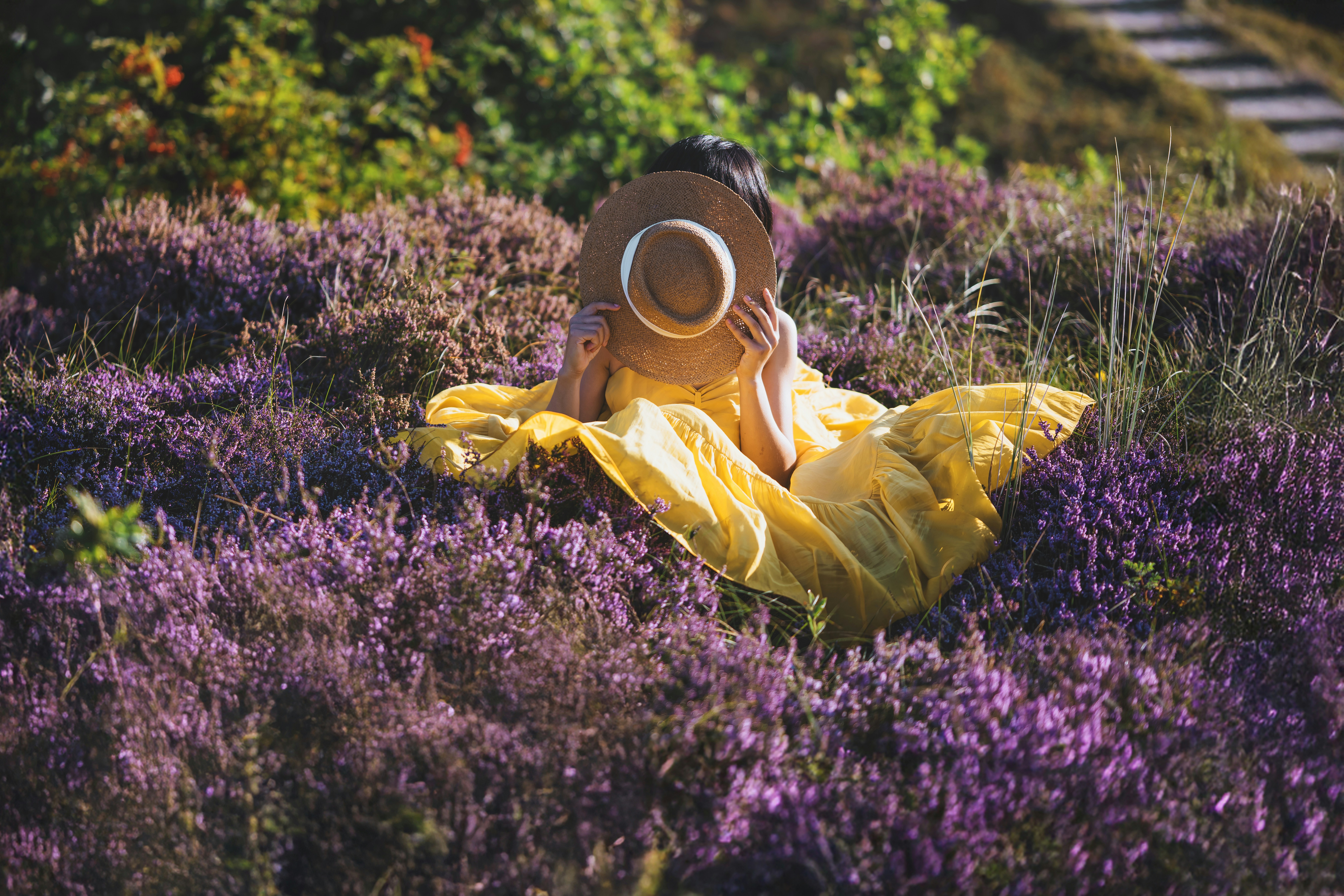 Woman in yellow dress sitting in purple heather field