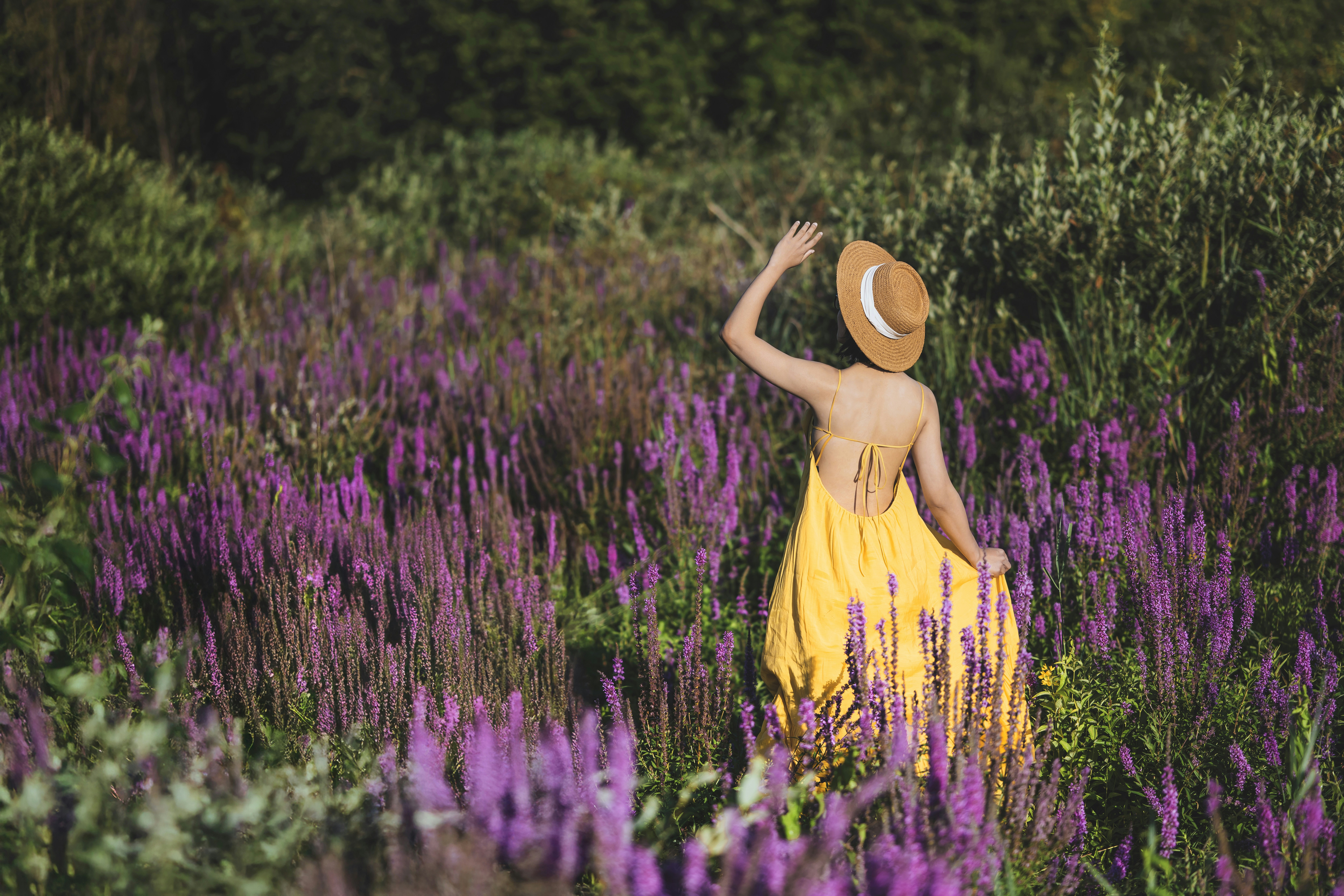 Woman in yellow dress walks through purple flowers