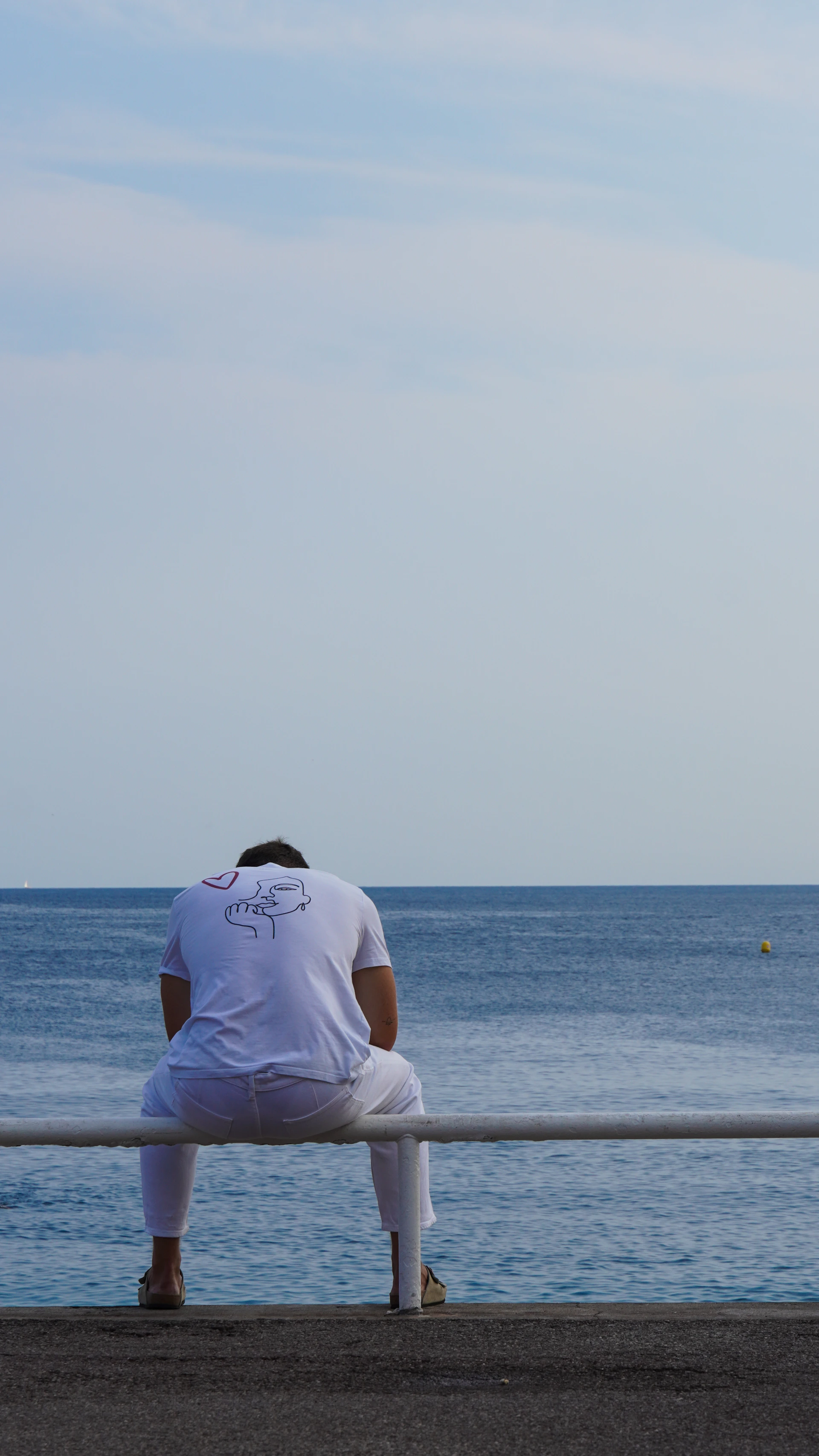 Man in white sitting by the ocean