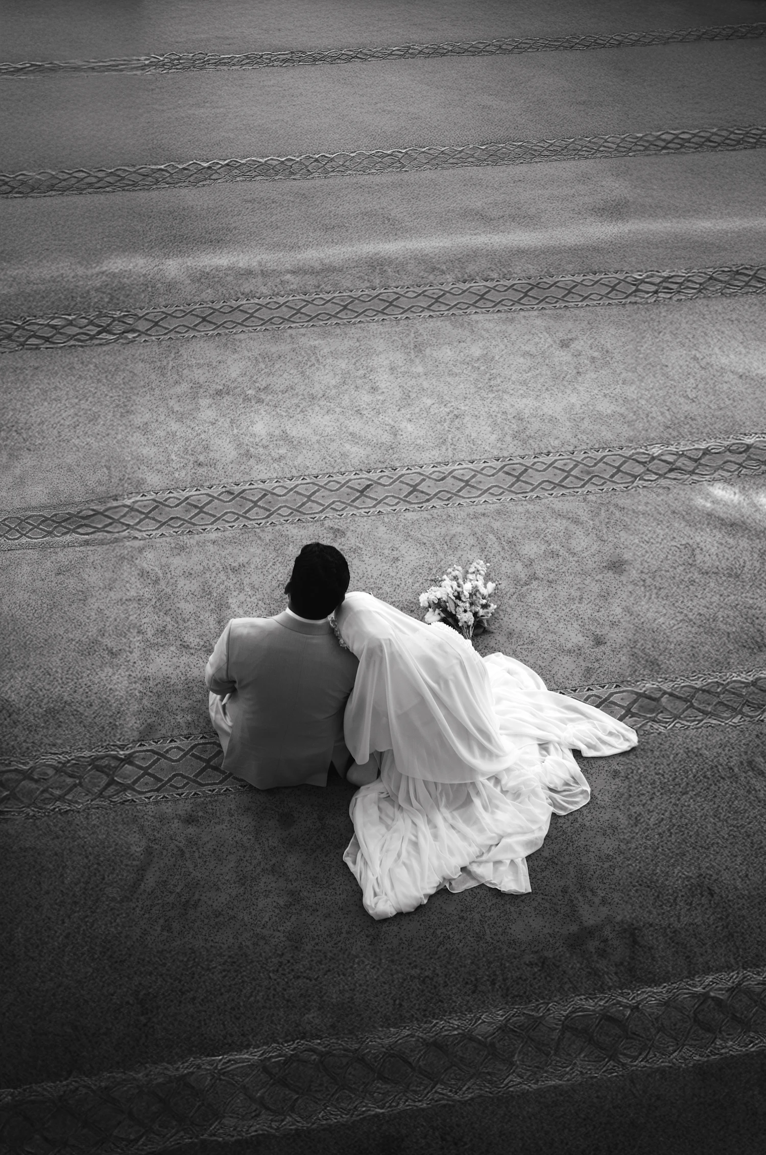 Seen from above, a couple sitting on wide stone steps with the dress spread behind them