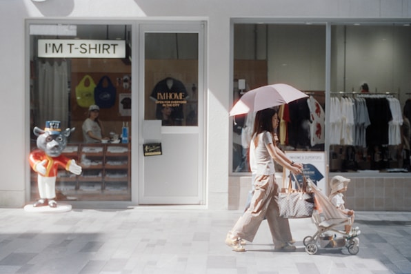 Woman pushes stroller past a t-shirt shop.