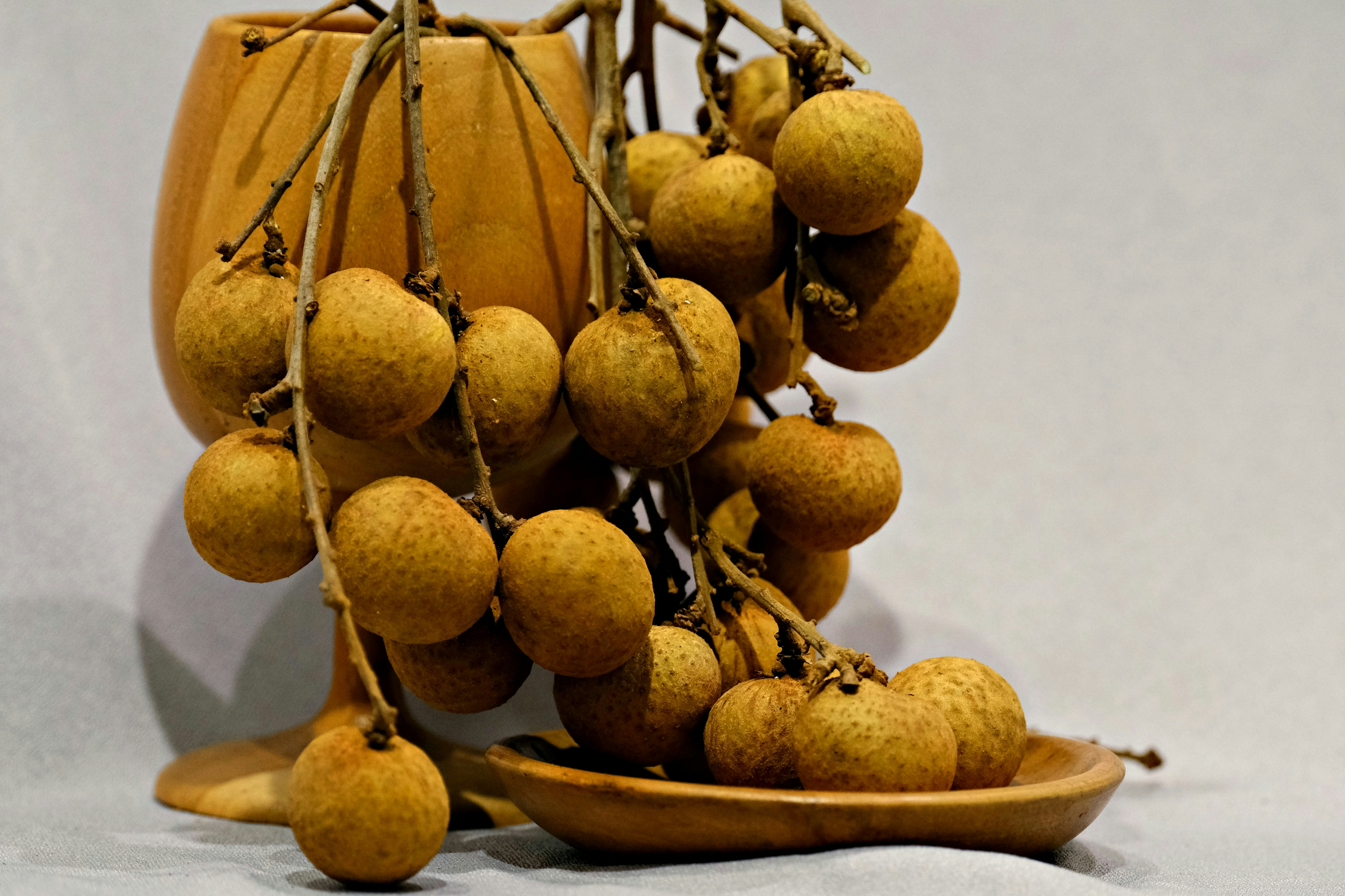 Frutas frescas de longan colgando de las ramas en un plato.
