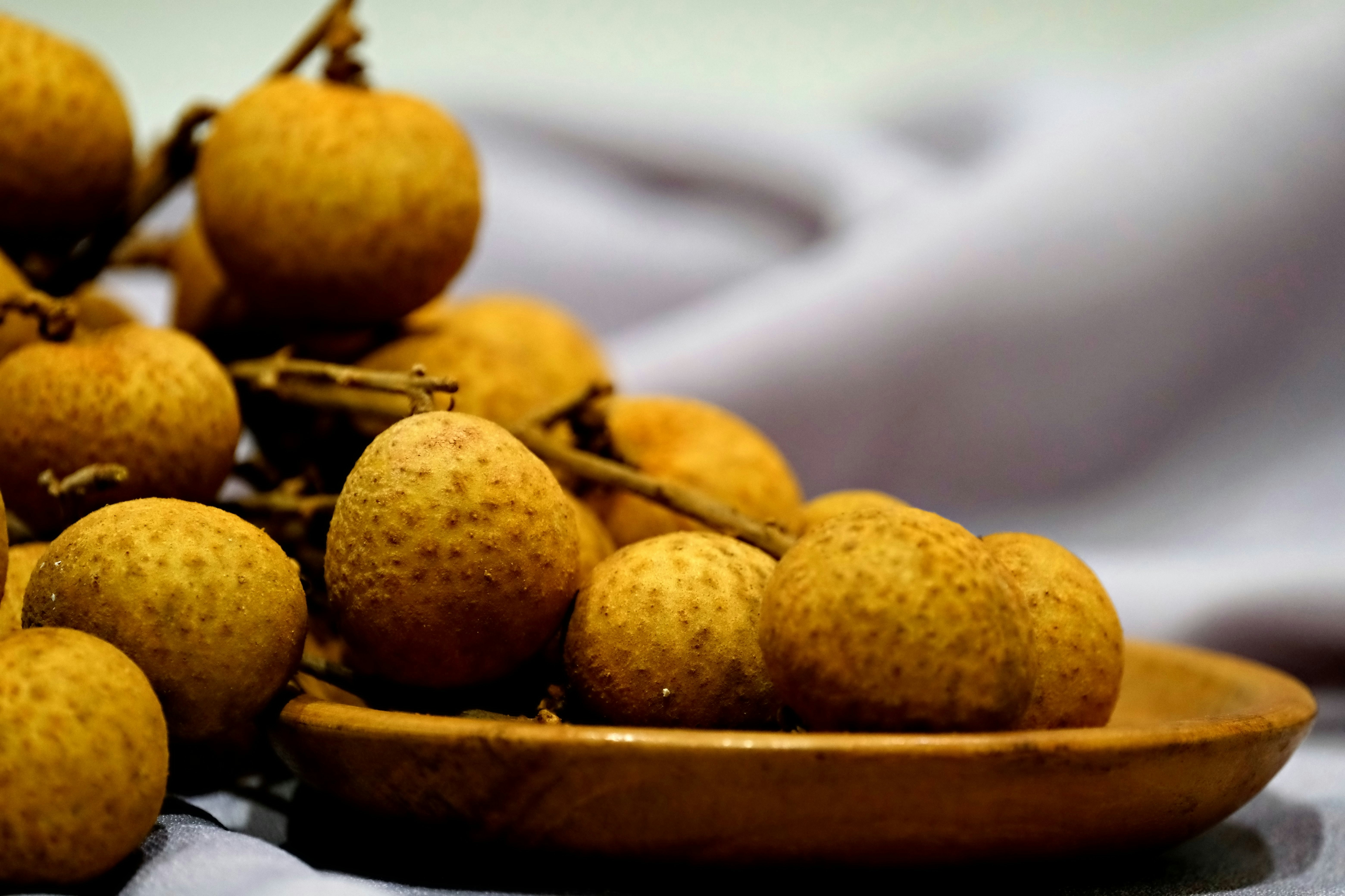 Tandan buah lengkeng matang dalam mangkuk kayu.