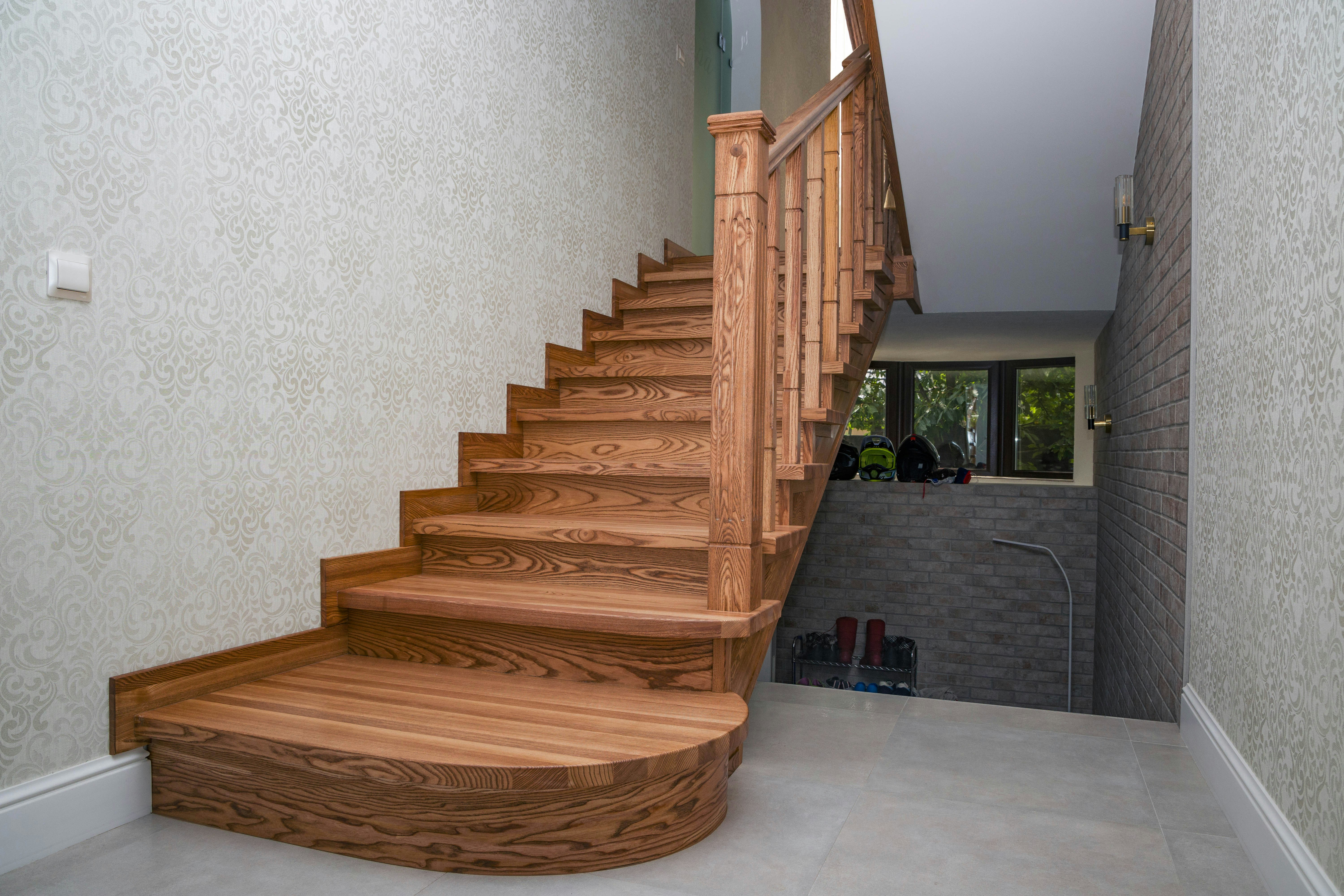 Wooden staircase with ornate banister and textured walls