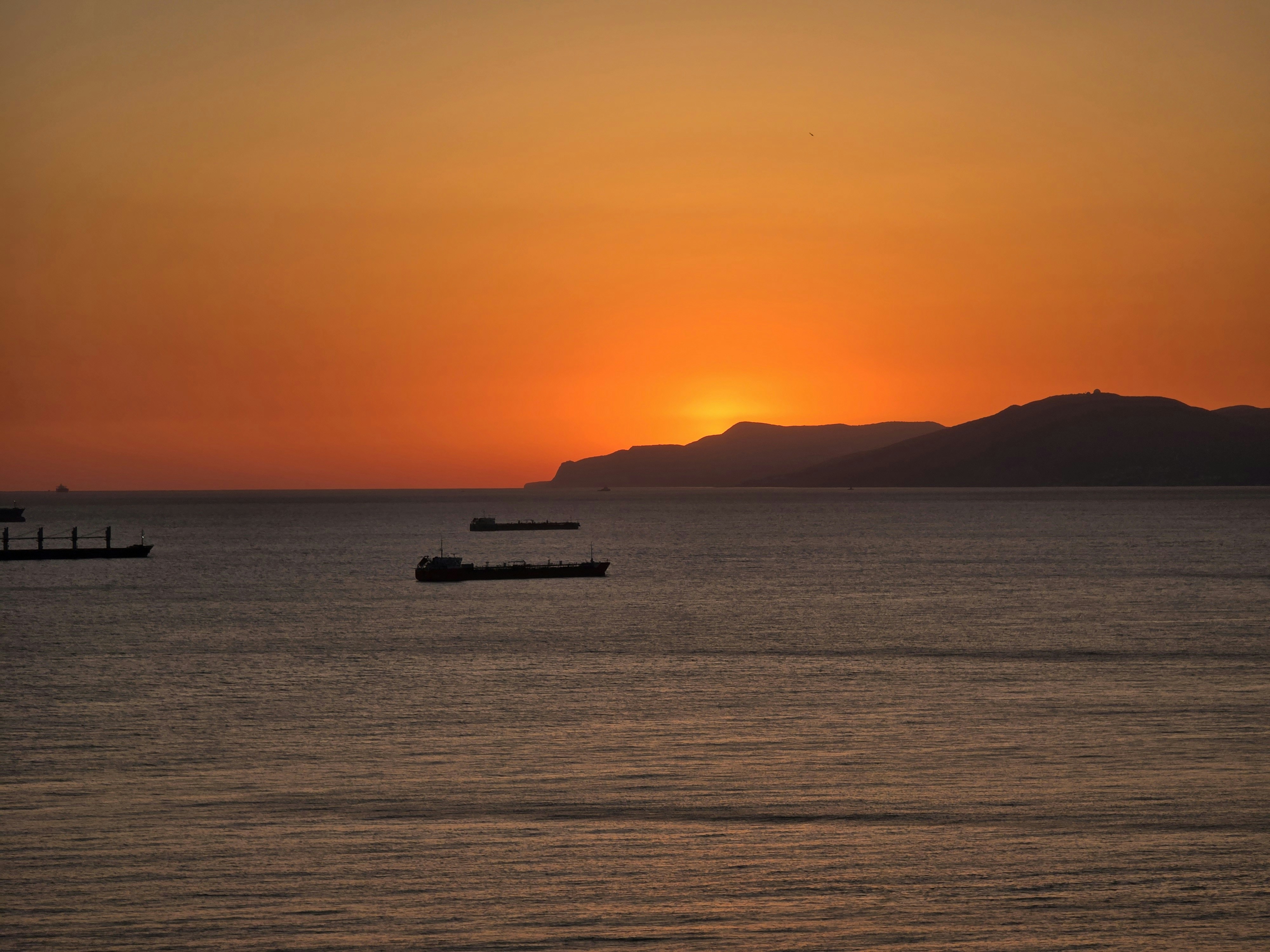 Ships on the water at sunset with mountains