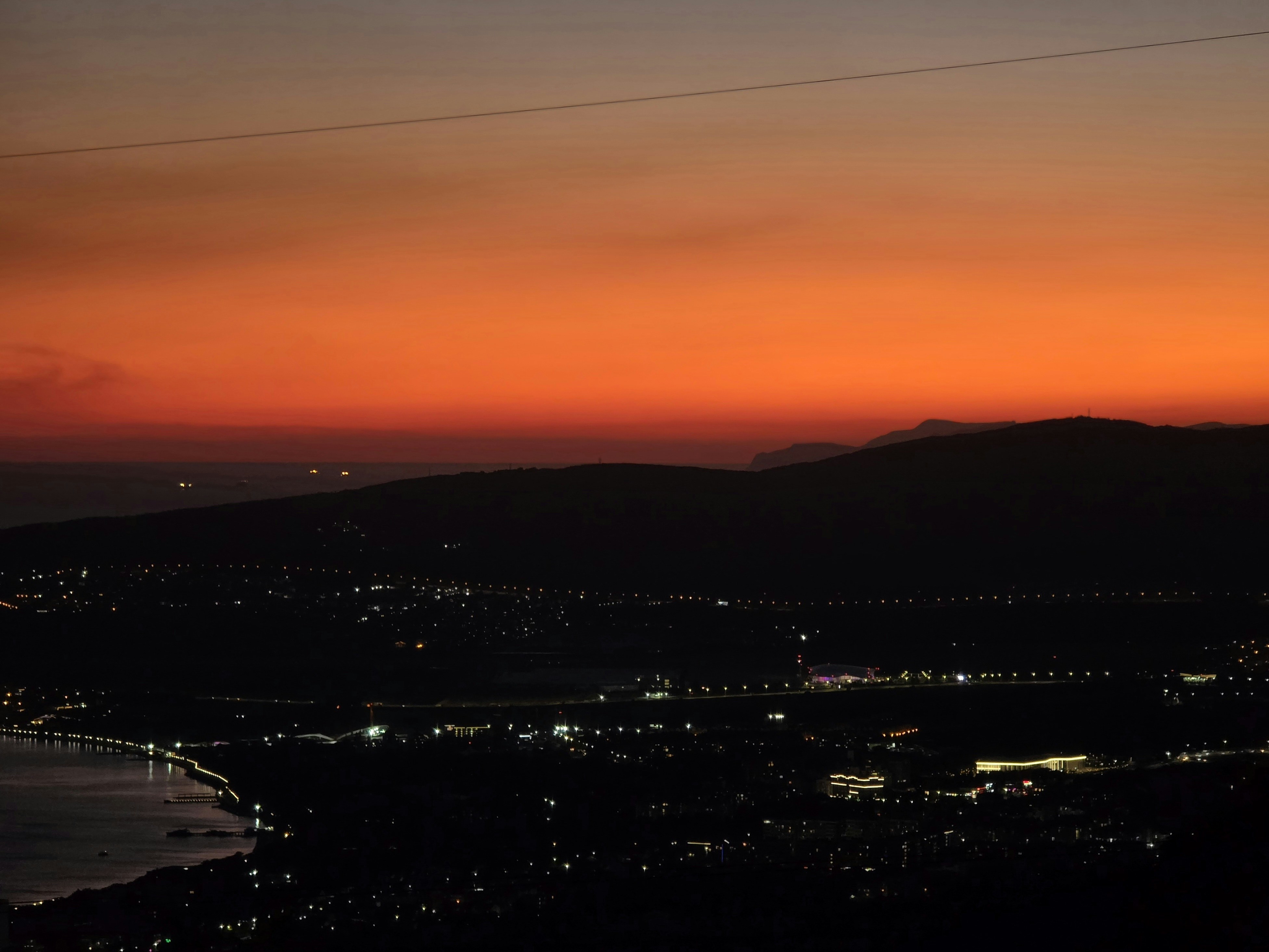 City lights twinkle under a vibrant sunset sky.