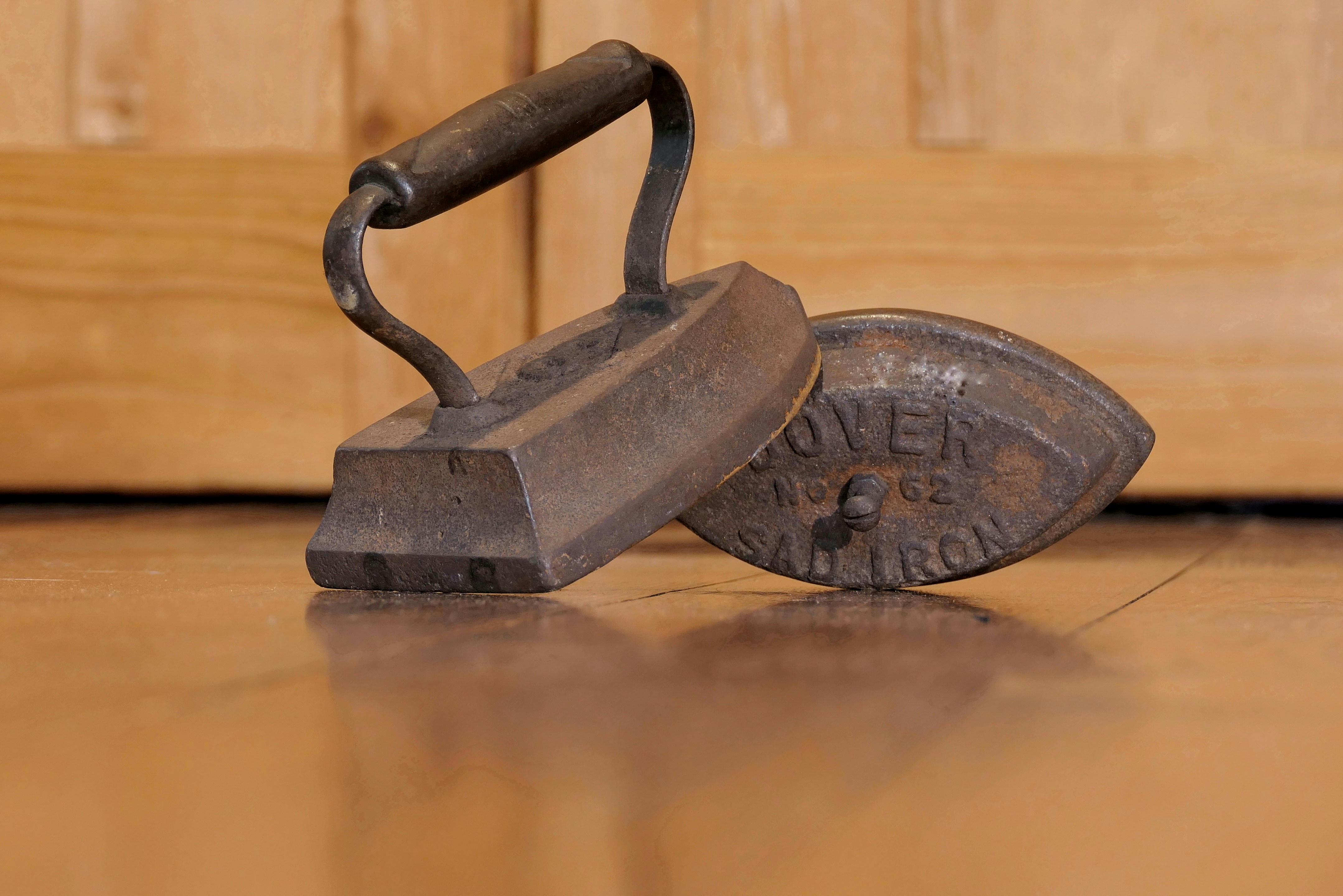 Deux fers à repasser anciens en fonte sur parquet.