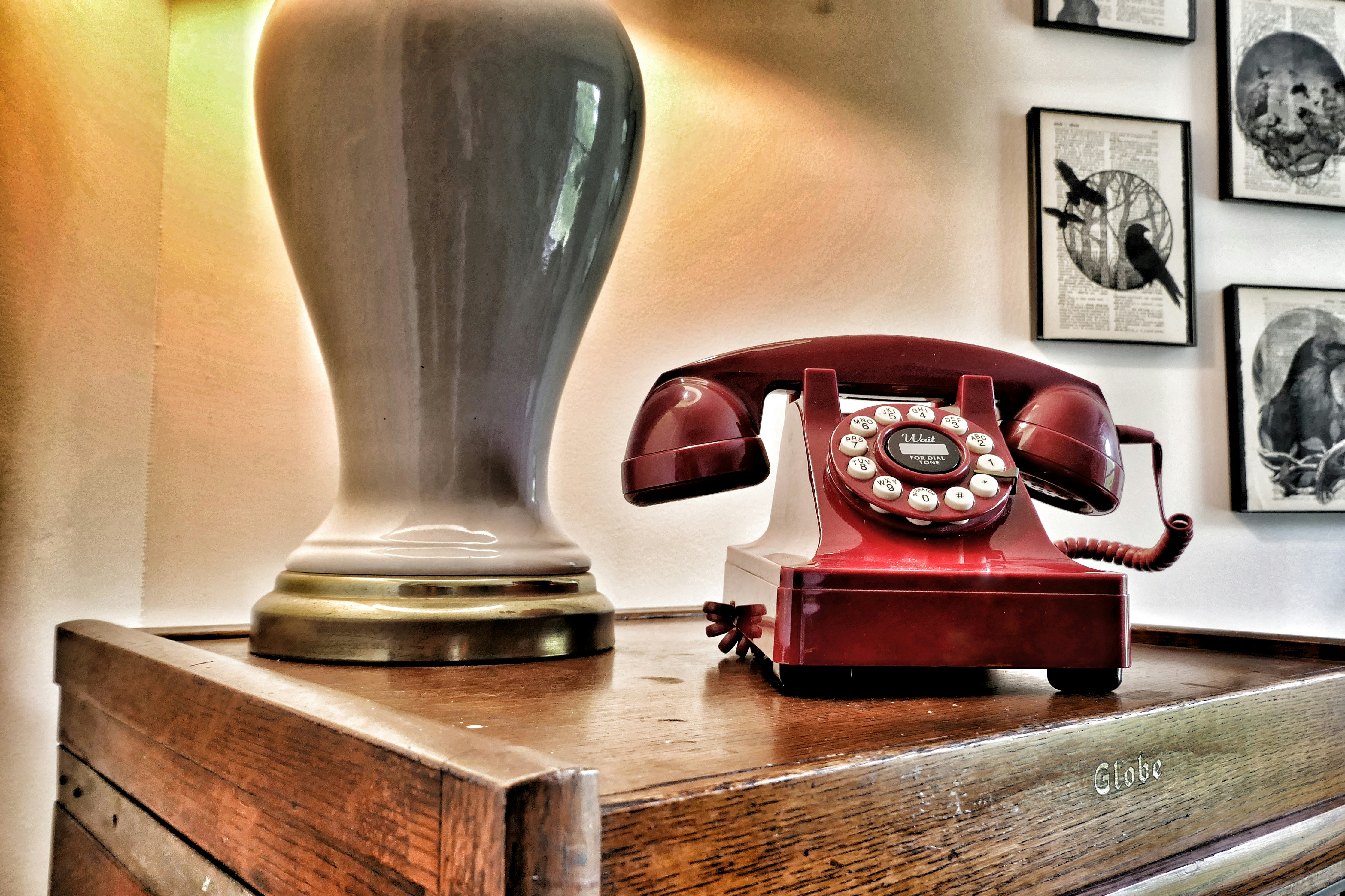 Vintage red rotary phone on wooden surface