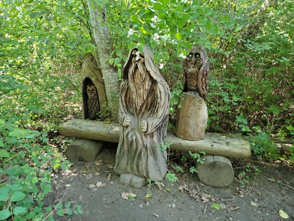 Wooden carvings of figures in a forest setting.